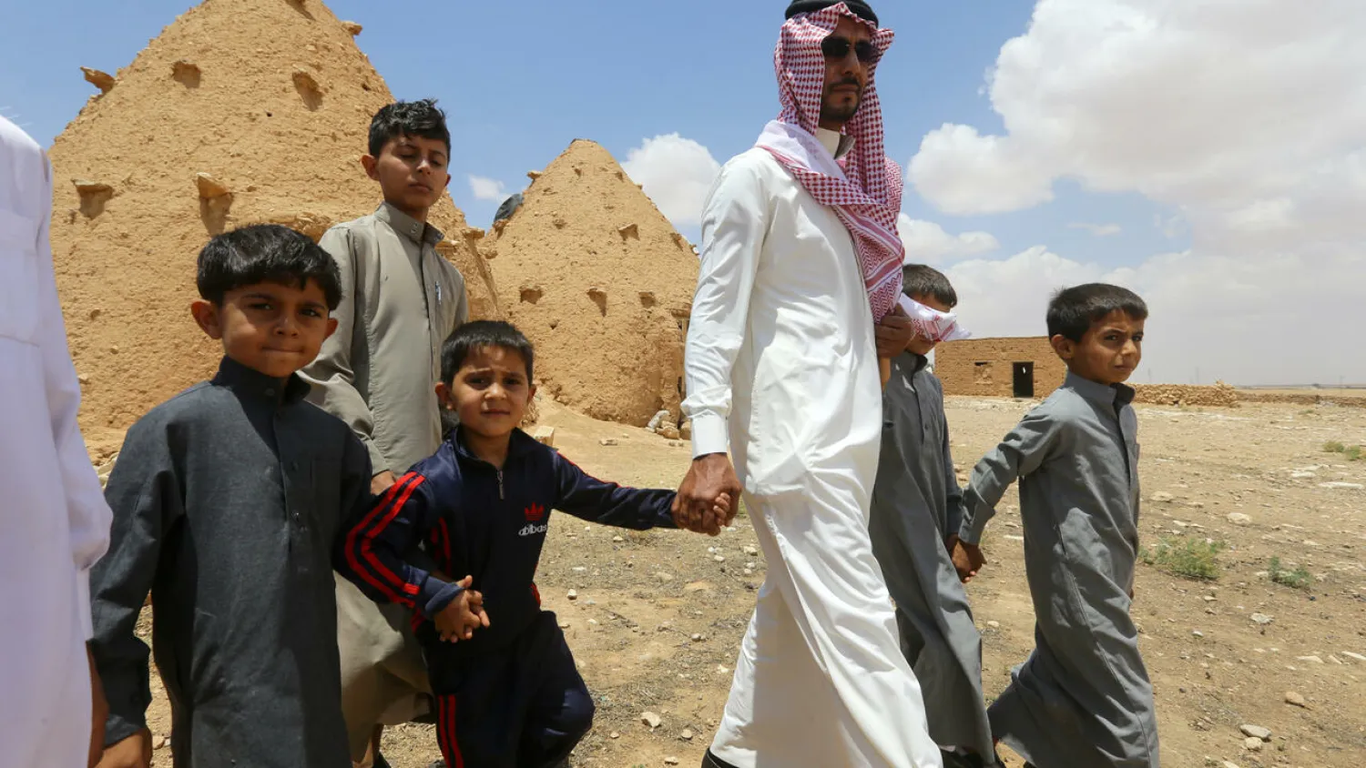Abdulaziz al-Oqab walks with his nephews who were orphaned when a landmine exploded under a pick-up truck, claiming the lives of 21 family members. AFP