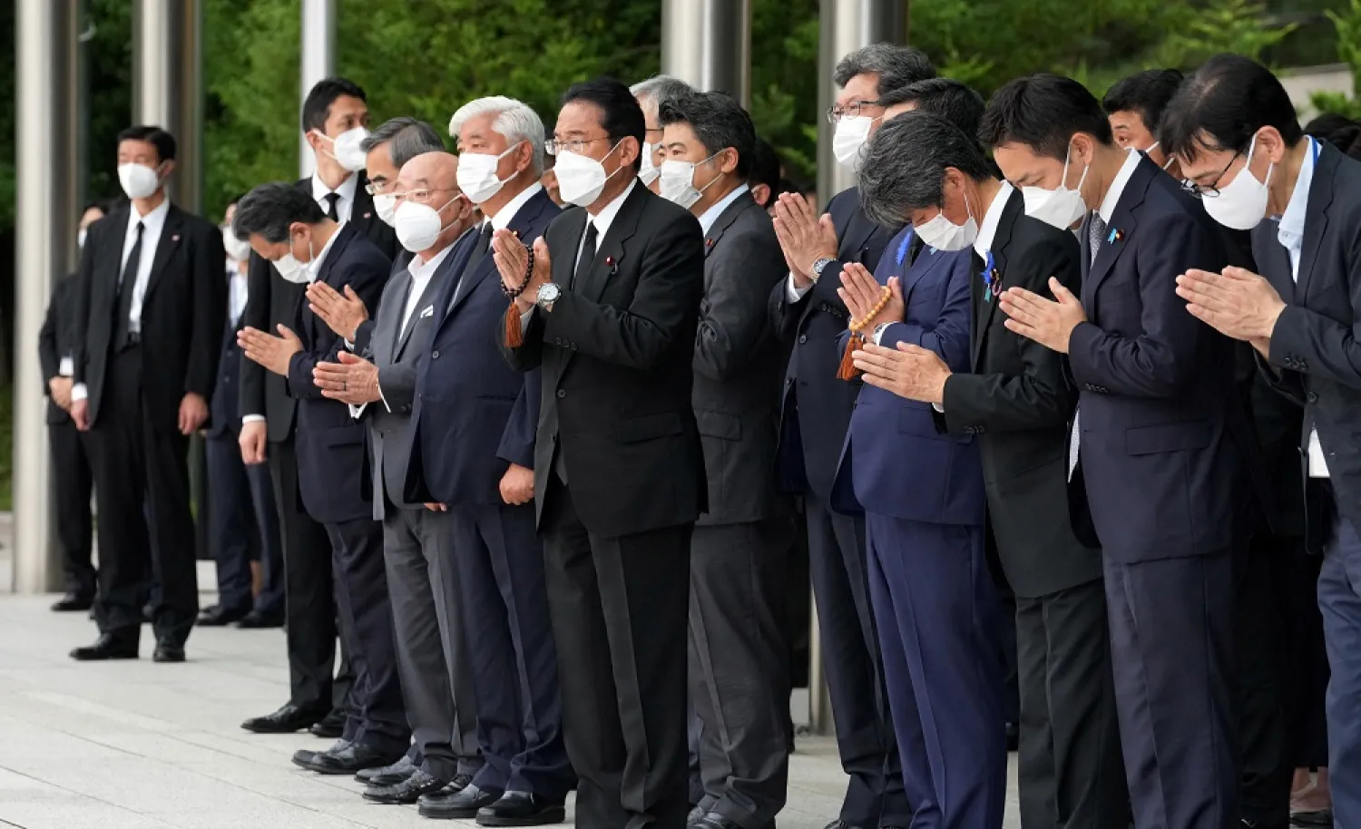 Japan's Prime Minister Fumio Kishida, officials and employees offer prayers towards a hearse as it carries the body of former Prime Minister Shinzo Abe, outside the Prime Minister's Office, in Tokyo, Japan July 12, 2022. (Reuters)