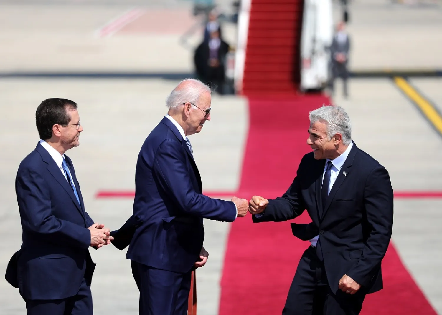 US President Joe Biden (L) fistbumps with Israeli Prime Minister Yair Lapid (R) as President Isaac Herzog (L) looks on upon arrival at Ben Gurion Airport, in Lod, Israel, 13 July 2022. (EPA)