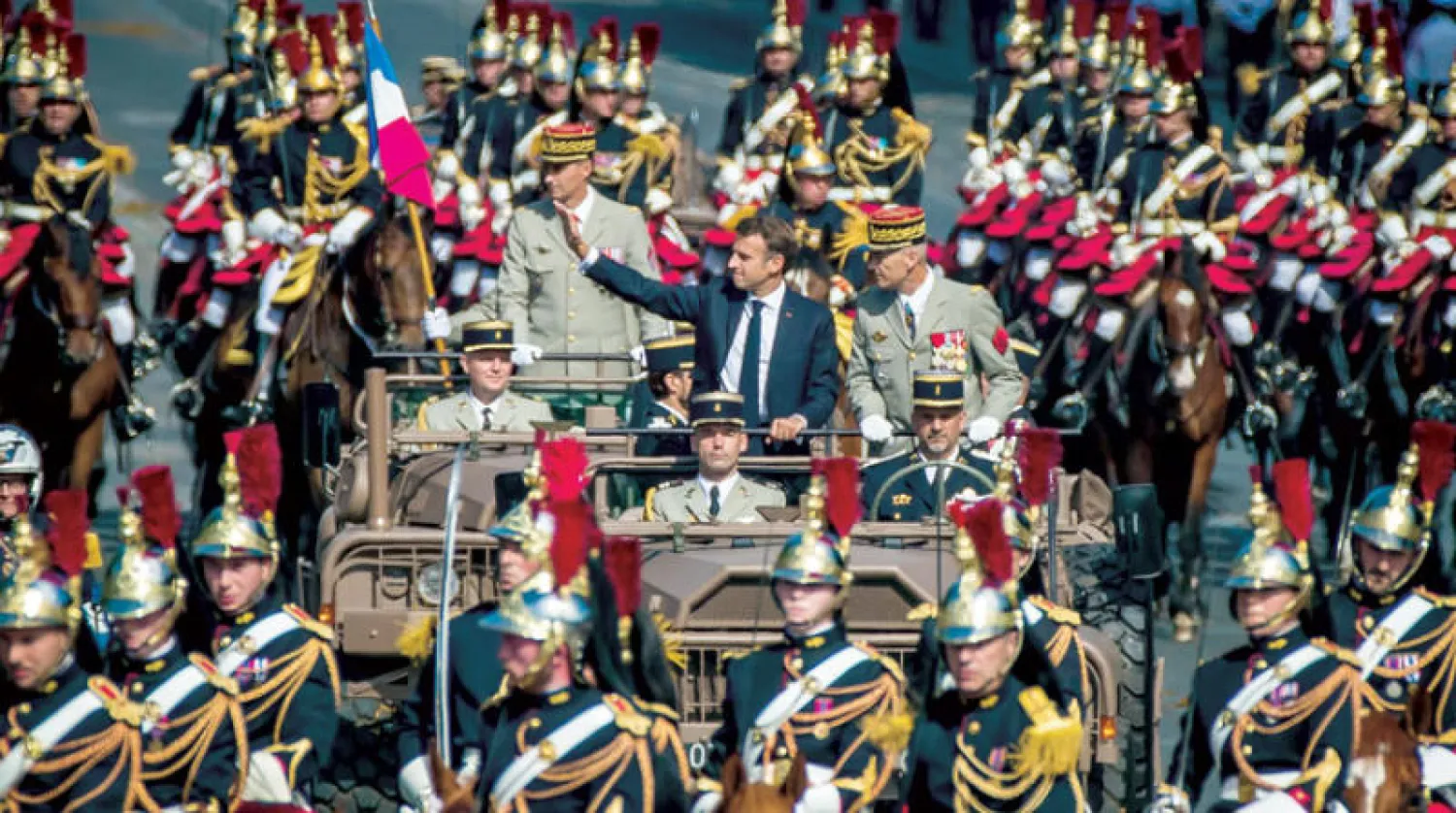 ماكرون وبجانبه رئيس الأركان الفرنسي يحيي الحضور في مستهل العرض العسكري بمناسبة العيد الوطني في باريس أمس (إ.ب.أ)