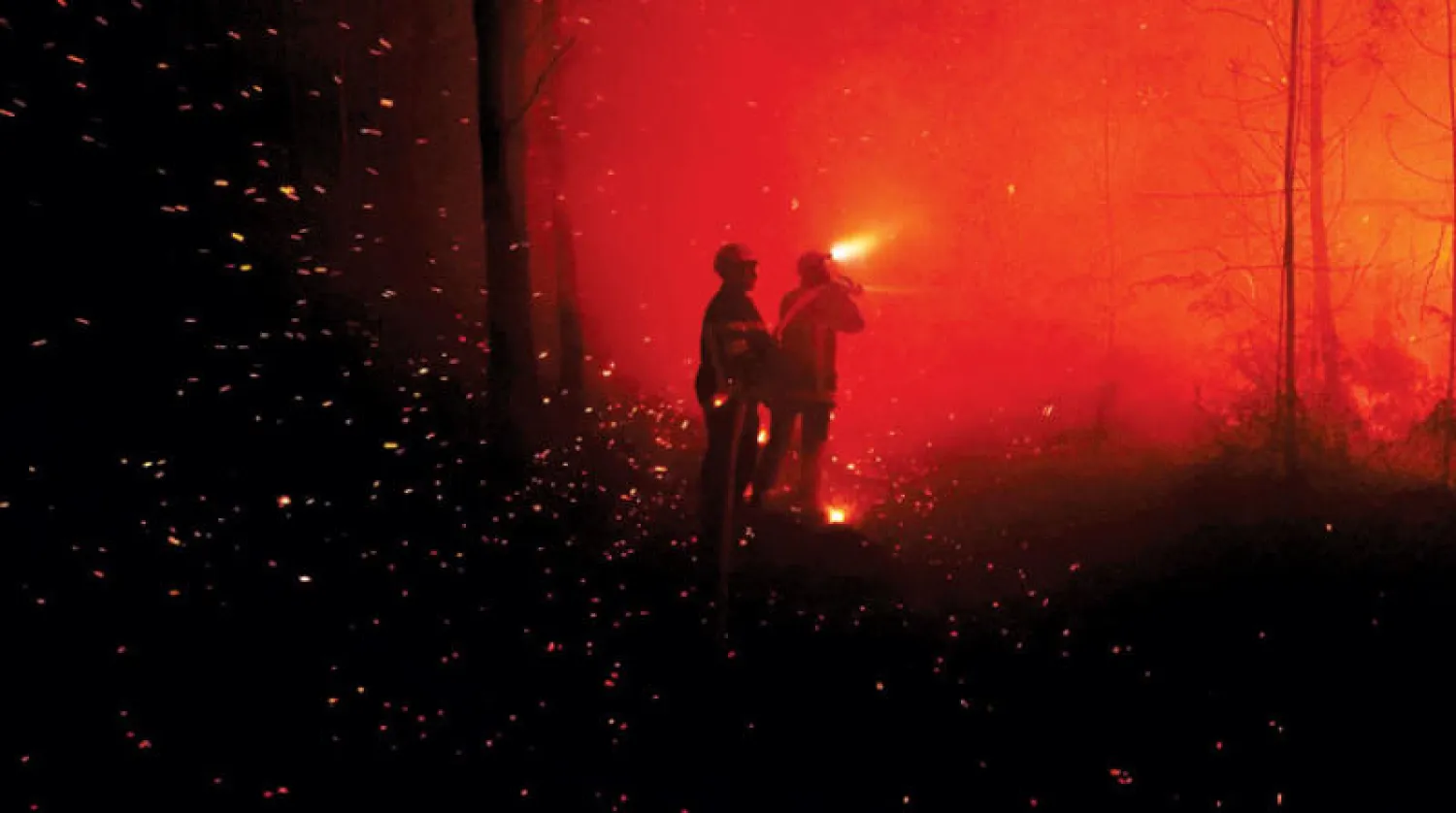 إطفائيان يكافحان حريقاً ضخماً قرب لانديراس في جنوب غربي فرنسا الليلة قبل الماضية (أ.ب)