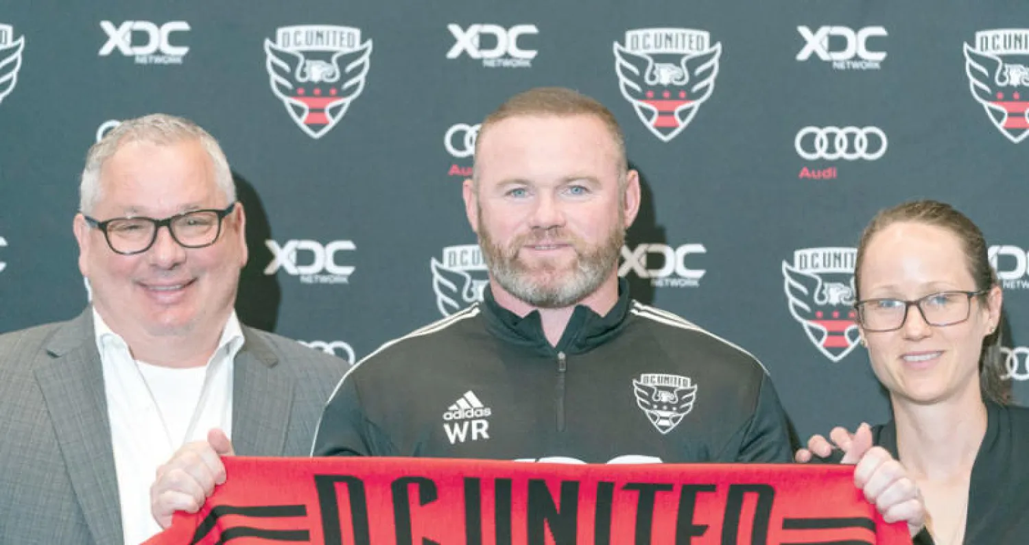 روني يتوسط كاسبر رئيس دي سي يونايتد (يسار) والمدير العام لوسي راشتون خلال إعلان تعيينه مدرباً (أ.ب)