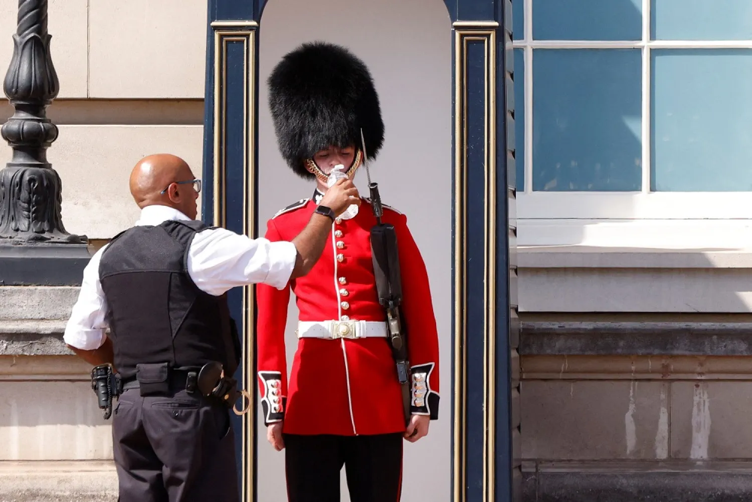 A member of the Queen's Guard receives water to drink during the hot weather, outside Buckingham Palace in London, Britain, July 18, 2022. (Reuters)
