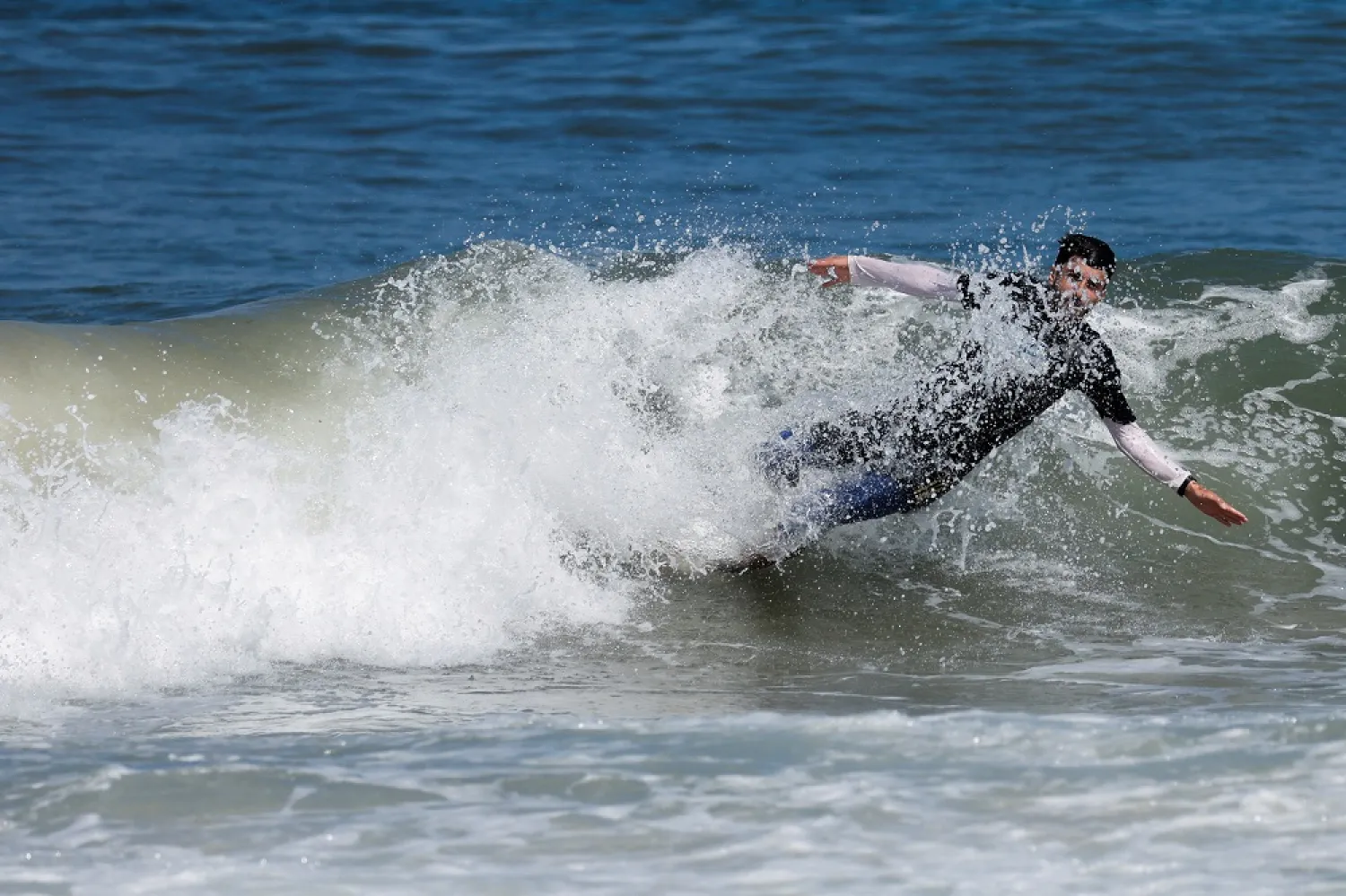 Palestinian surfer Mohammad Abu Ghanim surfs in the sea, in Gaza City July 12, 2022. (Reuters)