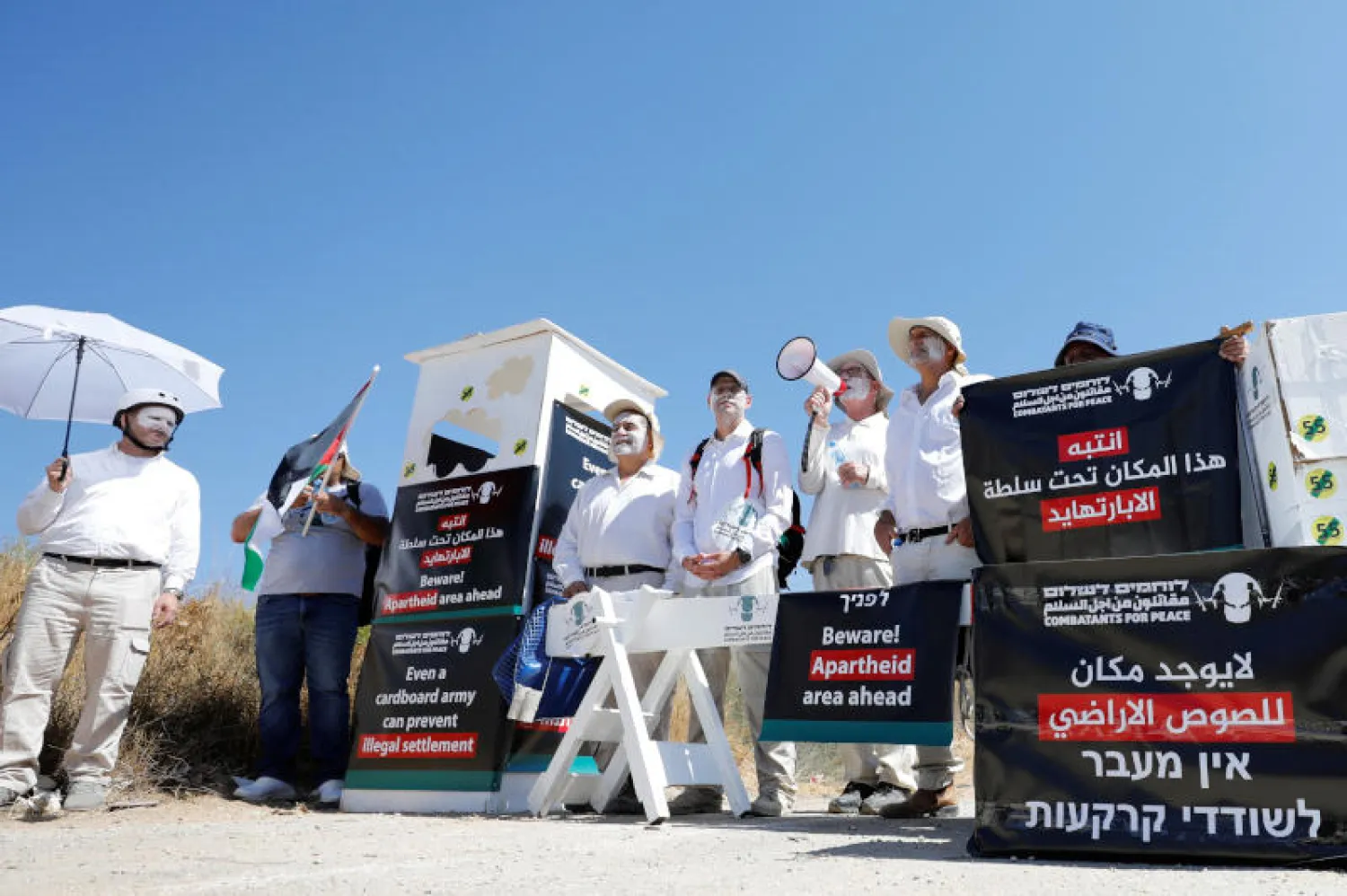 نشطاء سلام بجانب نقطة تفتيش وهمية للجيش الإسرائيلي احتجاجا على موقع استيطاني جديد في الضفة امس (رويترز)