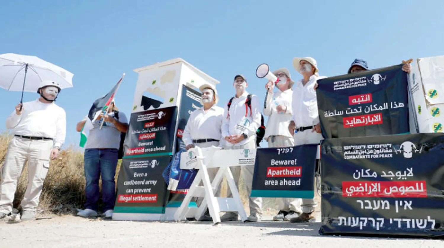 نشطاء سلام بجانب نقطة تفتيش وهمية للجيش الإسرائيلي احتجاجا على موقع استيطاني جديد في الضفة امس (رويترز)