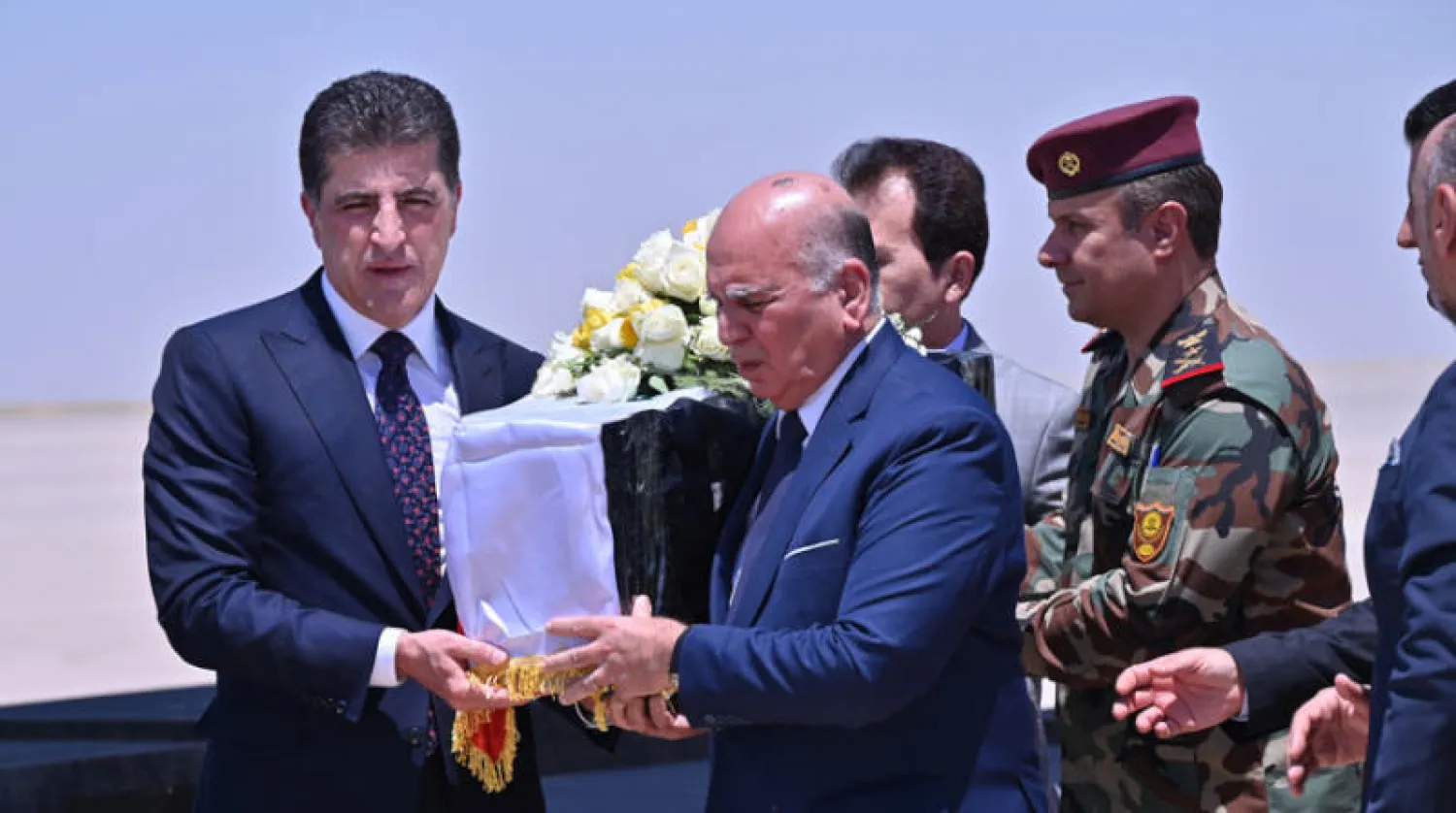 رئيس إقليم كردستان ووزير الخارجية العراقي يحملان نعش أحد الضحايا في مطار أربيل أمس (إ.ب.أ)
