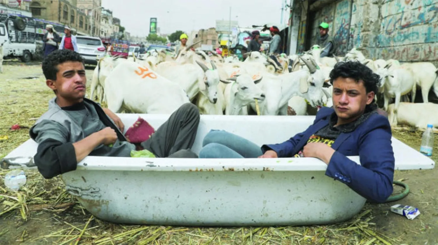 بائعا أغنام ينتظران زبائن خلال عيد الأضحى في صنعاء (رويترز)