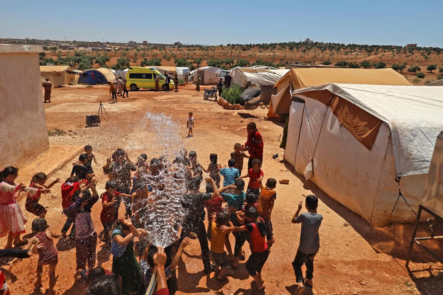 Children cool off at a camp for Syrians displaced by conflict near the Syrian border with Turkey in the opposition-held northern part of the northwestern Idlib province amidst high temperatures on July 20, 2022. (AFP) 