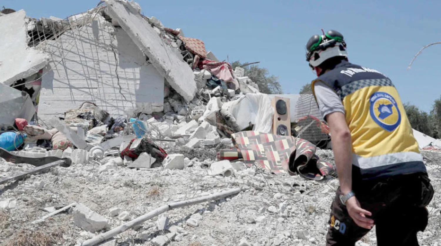 أحد عناصر الدفاع المدني السوري قرب أنقاض منزل دمرته غارة جوية روسية على أطراف مدينة جسر الشغور الجمعة (أ.ف.ب)