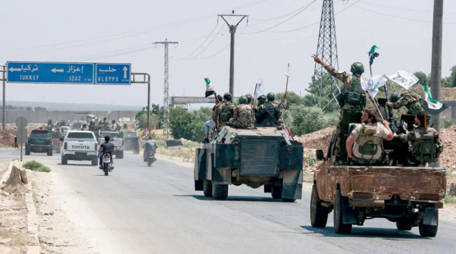 عرض عسكري لمقاتلين من الفصائل السورية المدعومة من تركيا بين بلدتي قطمة وإعزاز الحدوديتين في 2 يوليو (أ.ف.ب)