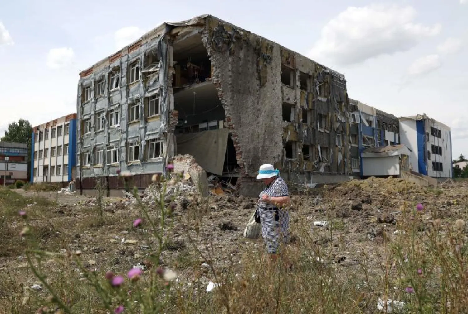 امرأة تمر أمام مبنى ضخم دمره القصف قي دونيتسك (أ.ف.ب)