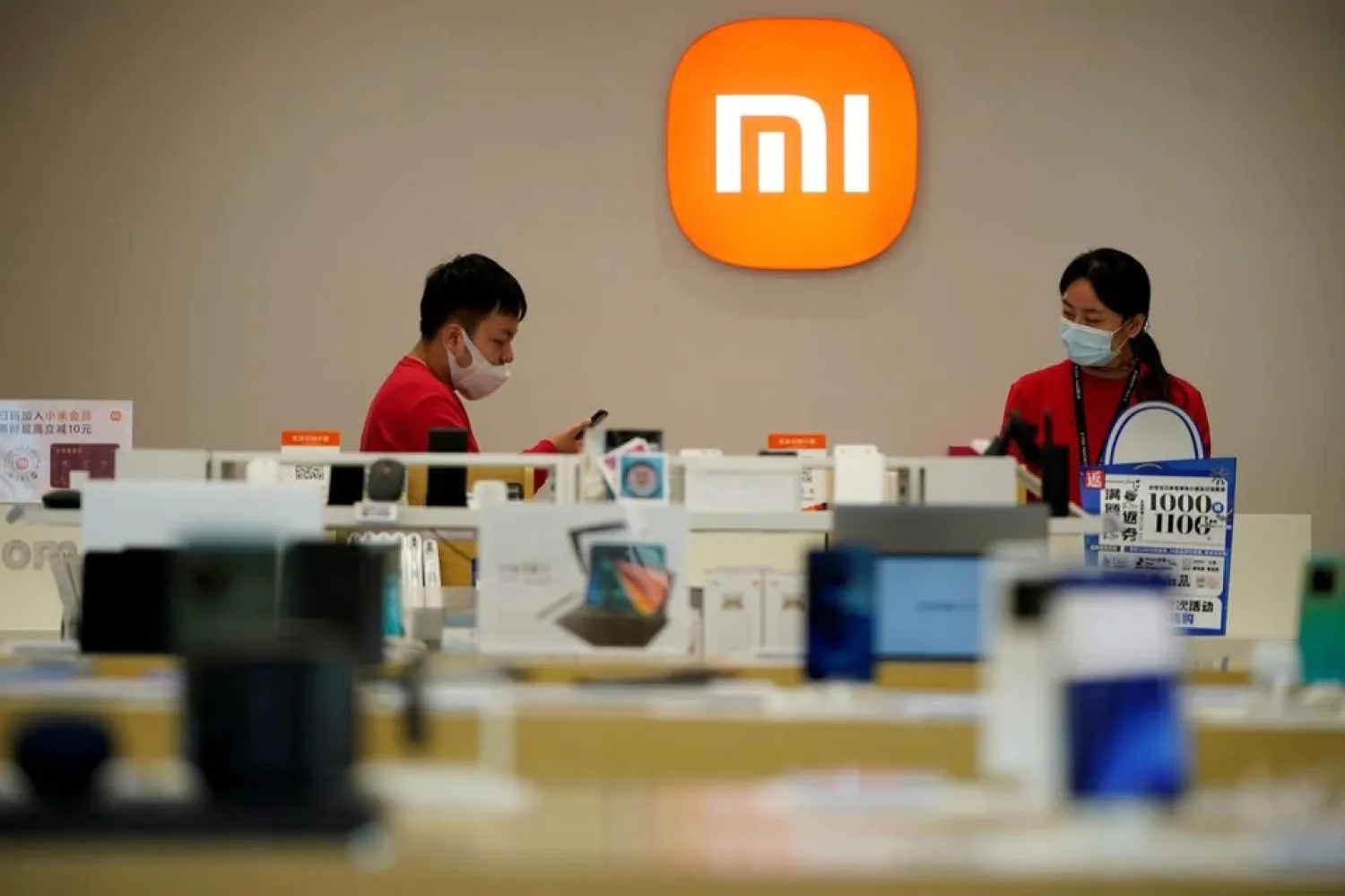 Staff members stand near the company logo at a Xiaomi store in Shanghai, China November 1, 2021. (Reuters)