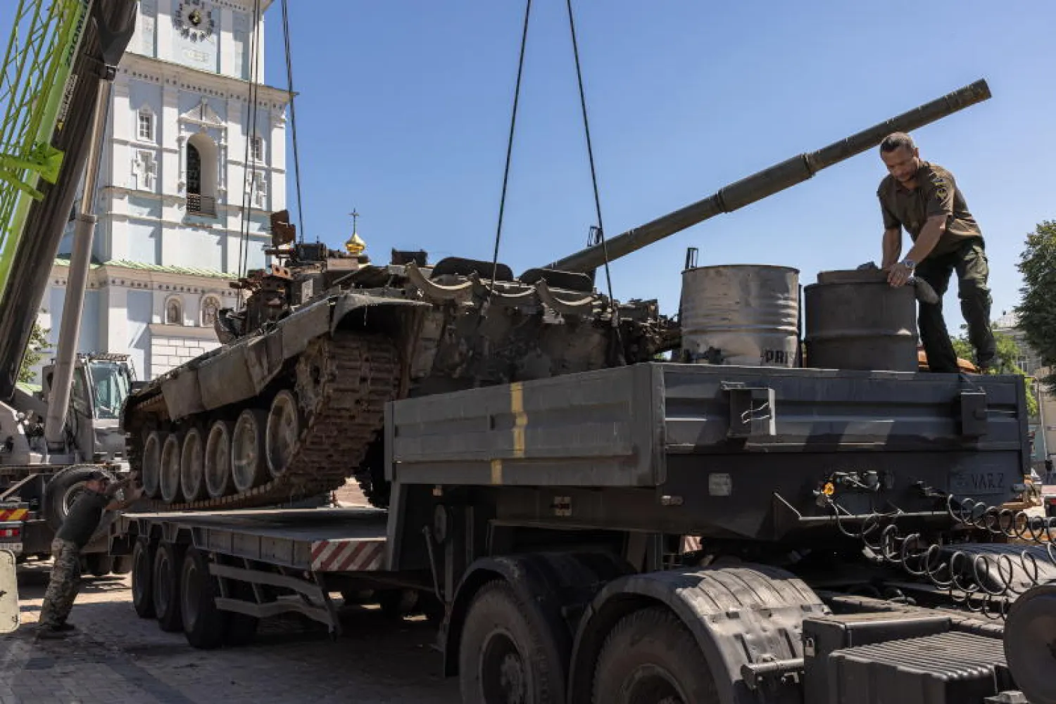 عسكريون أوكرانيون أثناء تحميل دبابة روسية مدمرة بميدان ميخايليفسكي في كييف(إ.ب.أ)