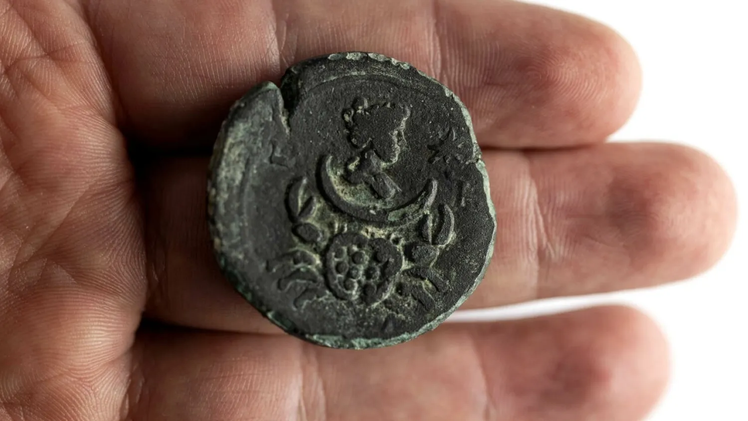 This picture taken at the office of Israel's Antiquities Authority in Jerusalem on July 26, 2022 shows a 1850-year-old rare coin depicting the moon goddess recently recovered from the sea off the Carmel coast in the northern city of Haifa. (Photo by MENAHEM KAHANA / AFP)