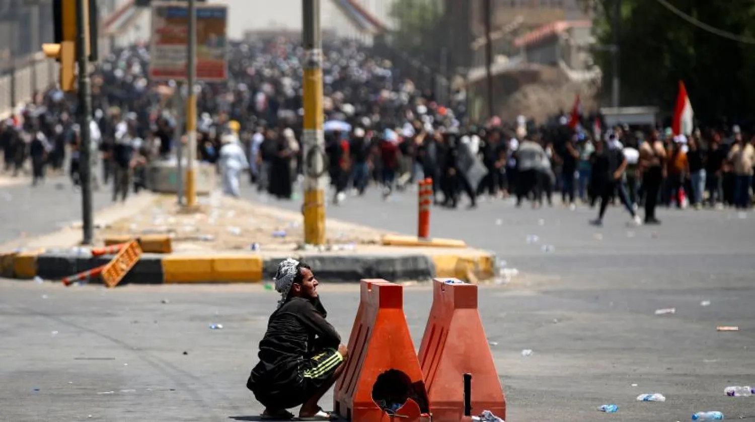 Bağdat'ın merkezindeki bir gösteri sırasında güvenlik güçleriyle çatışan bir Iraklı saklanıyor (AFP)
