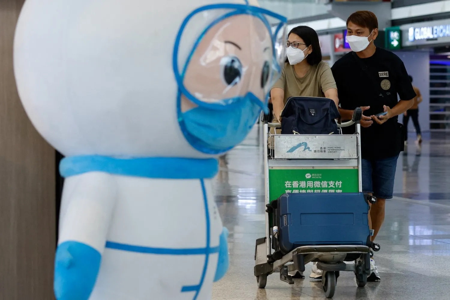 Travelers walk past an installation featuring a medical worker at the Hong Kong International Airport Departure Hall, amid the coronavirus disease (COVID-19) pandemic, in Hong Kong, China, August 1, 2022. (Reuters)