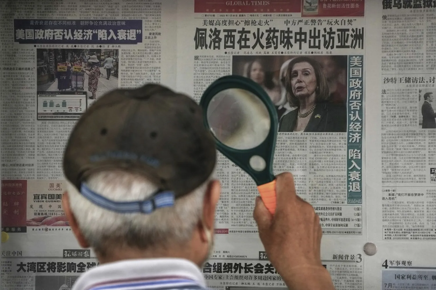 A man uses a magnifying glass to read a newspaper headline reporting on US House Speaker Nancy Pelosi's Asia visit, at a stand in Beijing, Sunday, July 31, 2022. (AP)