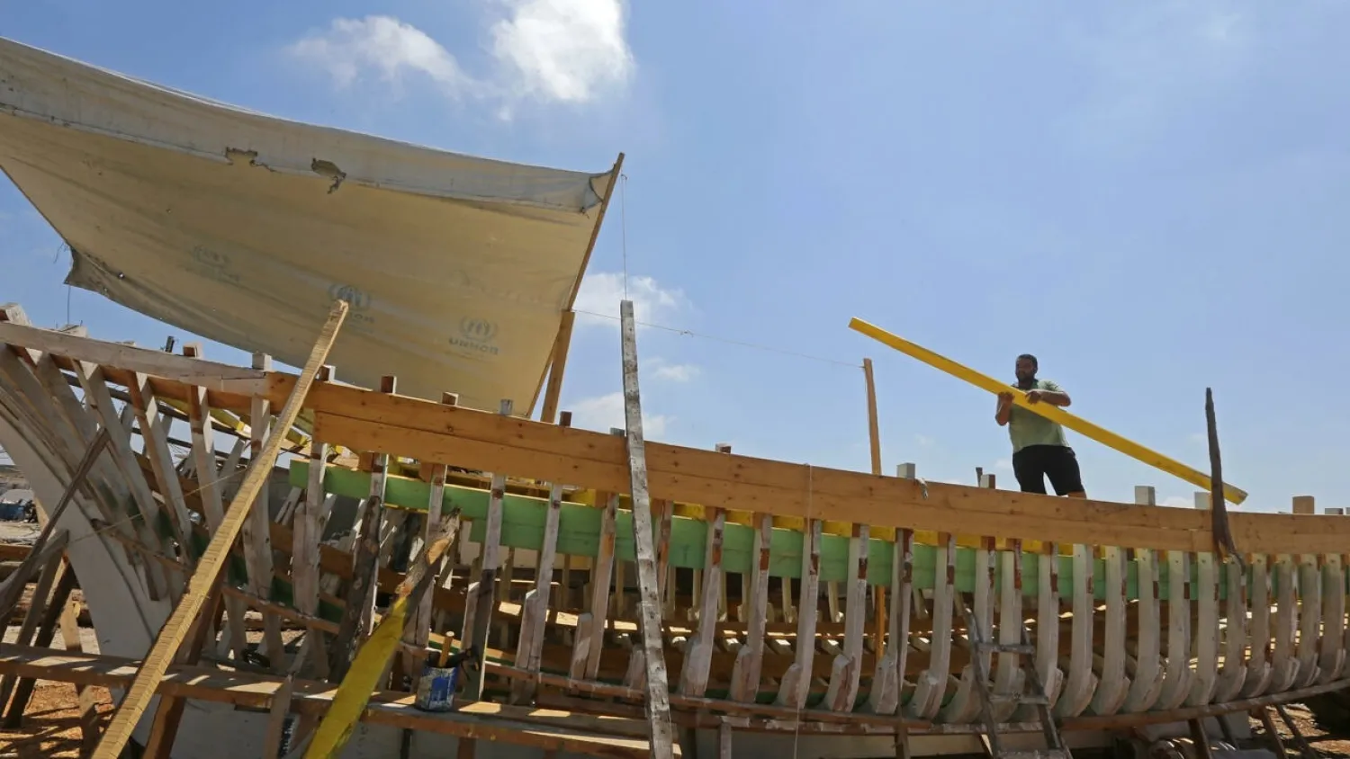 Syrian craftsman Khaled Bahlawan builds a wooden boat at his boatyard in Syria's Mediterranean Island of Arwad on July 24, 2022. (Photo by LOUAI BESHARA / AFP)