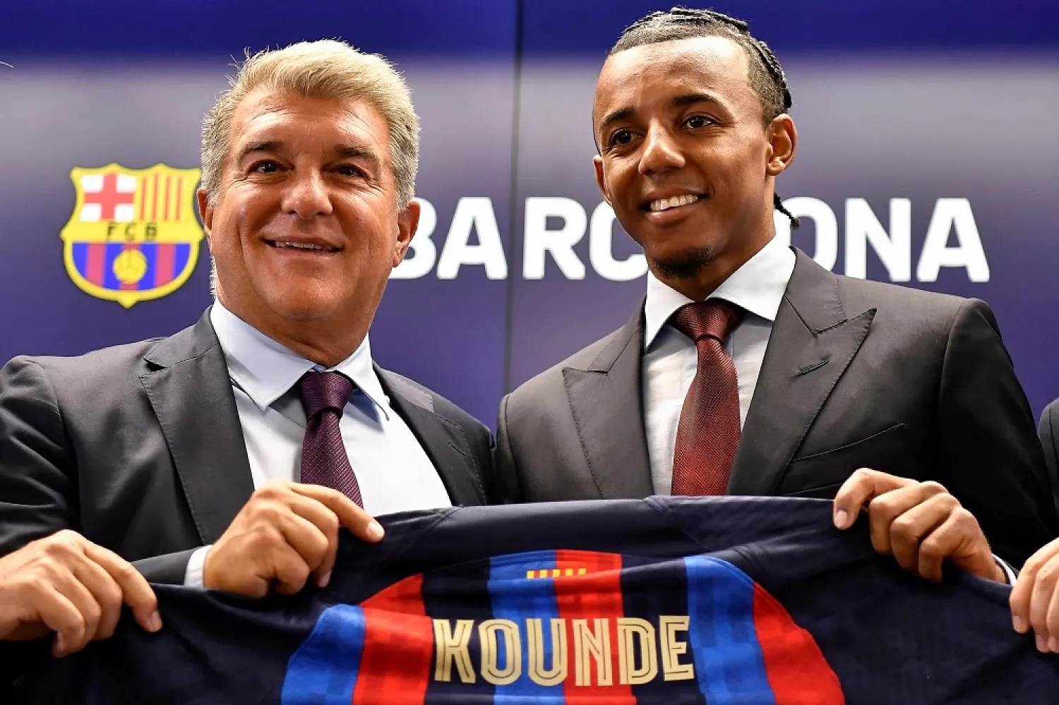 FC Barcelona's new french defender Jules Koundé (R) poses for pictures holding his new jersey with Barcelona's Spanish President Joan Laporta during a press conference as part of his presentation ceremony at the Joan Gamper training ground in Sant Joan Despi, near Barcelona, on August 1, 2022. (AFP)