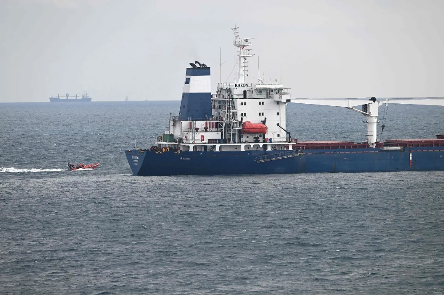 This photograph taken on August 3, 2022, shows a coastal safety boat cruising near the Sierra Leone-flagged cargo ship Razoni carrying 26,000 tons of corn from Ukraine, off the coast of north-west Istanbul, as it waits for an inspection delegation. (AFP)
