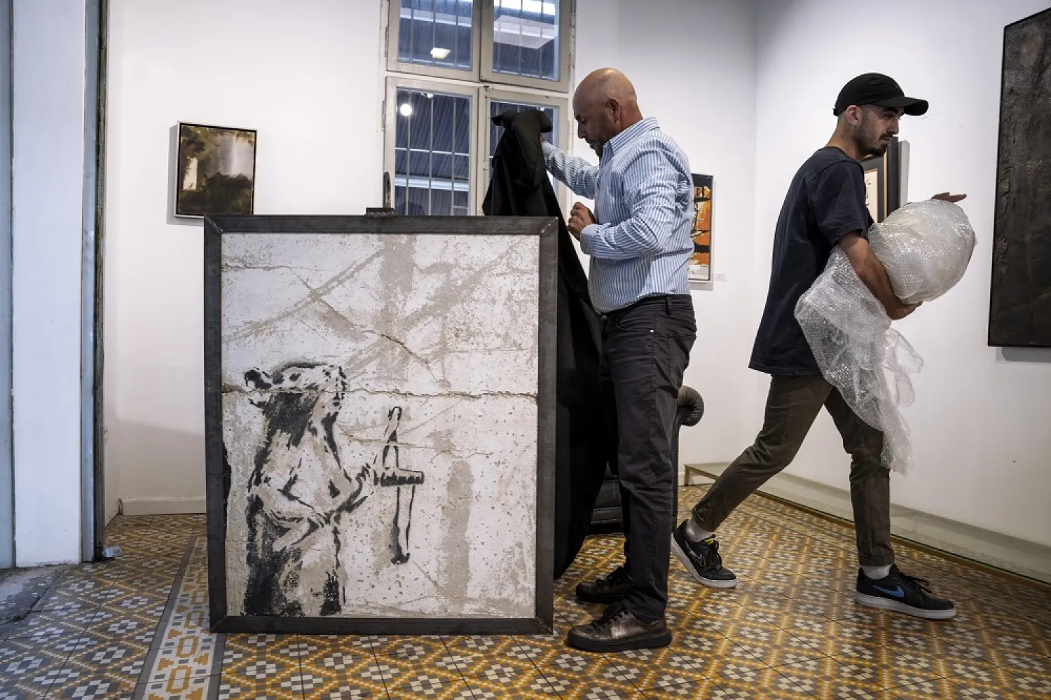Koby Abergel, an Israeli art dealer, reveals a painting by the secretive British graffiti artist Banksy that was mysteriously transferred from the occupied West Bank to the Urban Gallery in Tel Aviv, Israel, Thursday, Aug. 4, 2022. (AP)