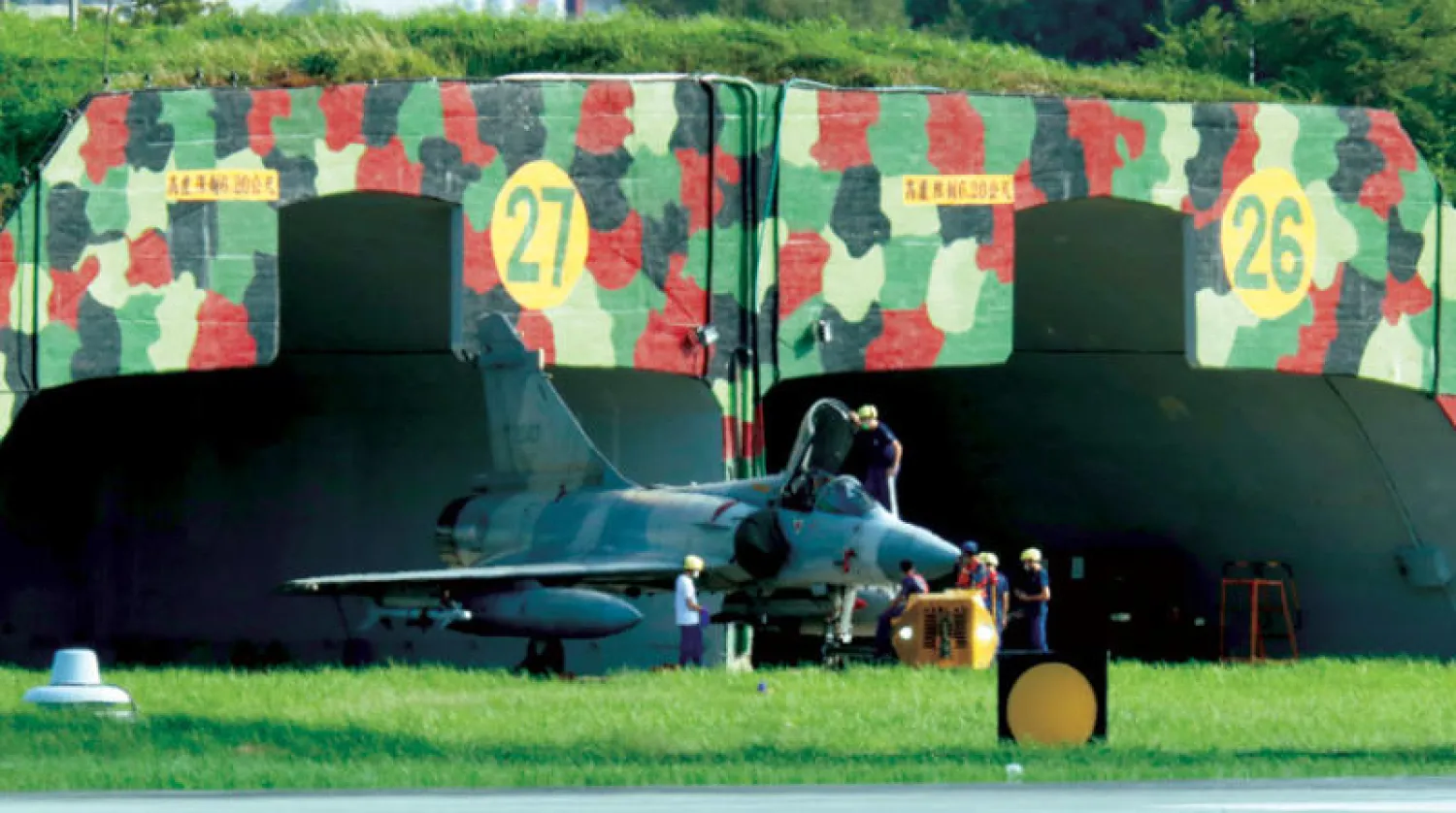أفراد من قوات تايوان الجوية يتفقدون طائرة حربية في قاعدة هينشو أمس (إ.ب.أ)