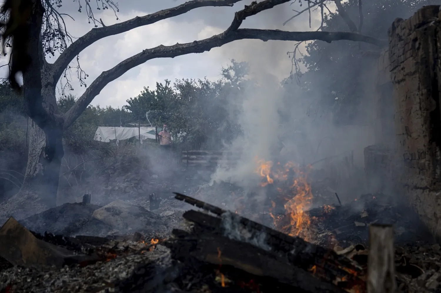 A local resident, back, tries to stop the fire at a neighbor's house destroyed by a Russian attack in Mykolaiv, Ukraine, Friday, Aug. 5, 2022. (AP)