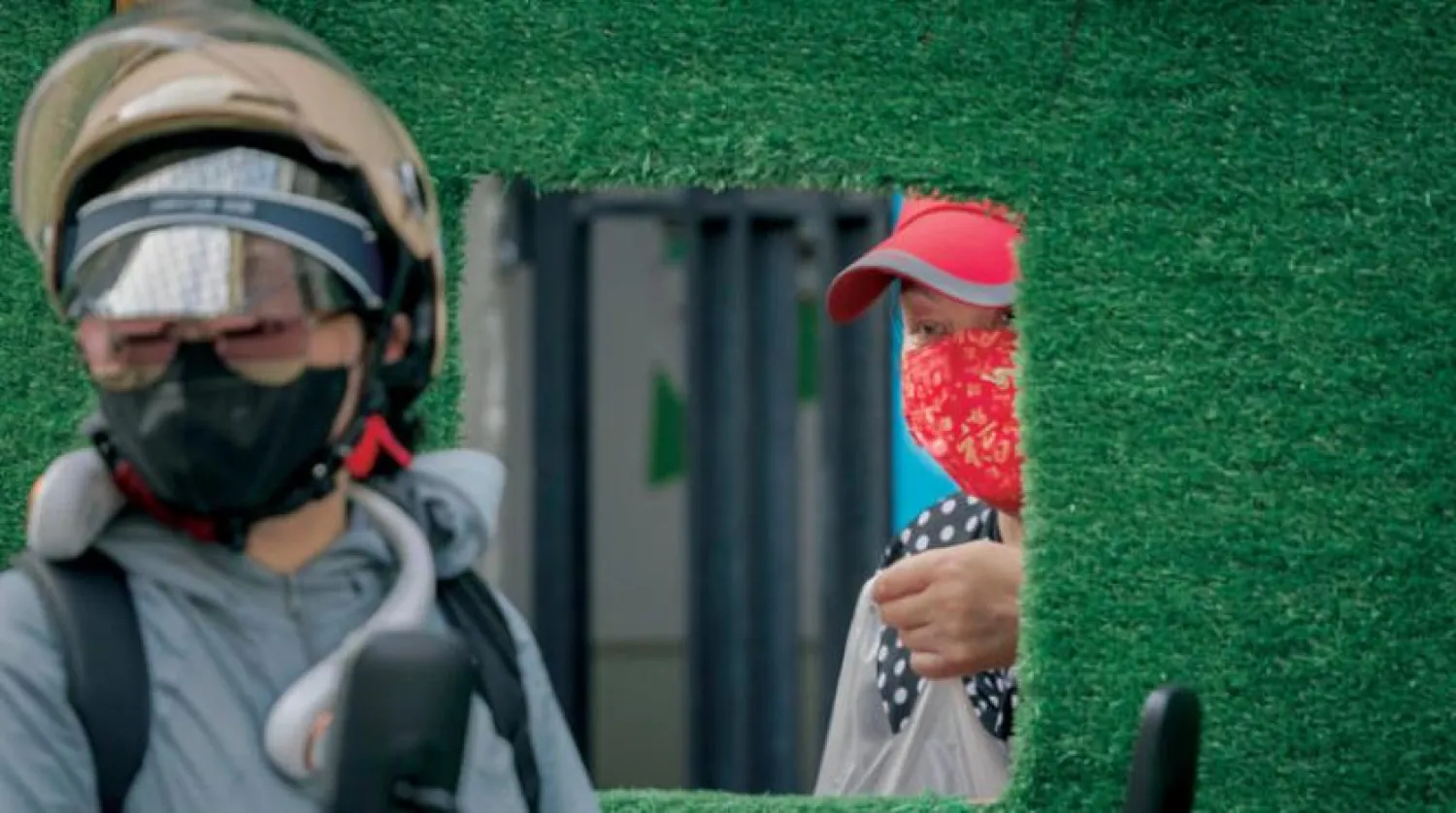 12 Temmuz 2022’de Şanghay’da karantina sırasında bariyerdeki pencereden yiyecek alan bir kadın (EPA)