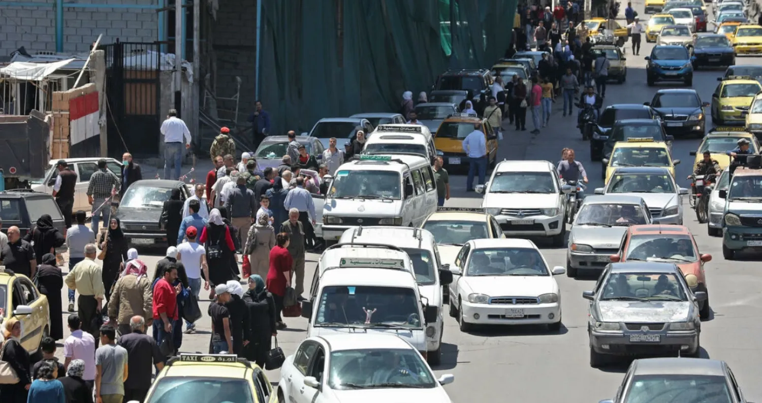 In this file photo taken on May 10, 2020, pedestrians walk along a line of cars in a busy street in the Syrian capital Damascus LOUAI BESHARA AFP/File
