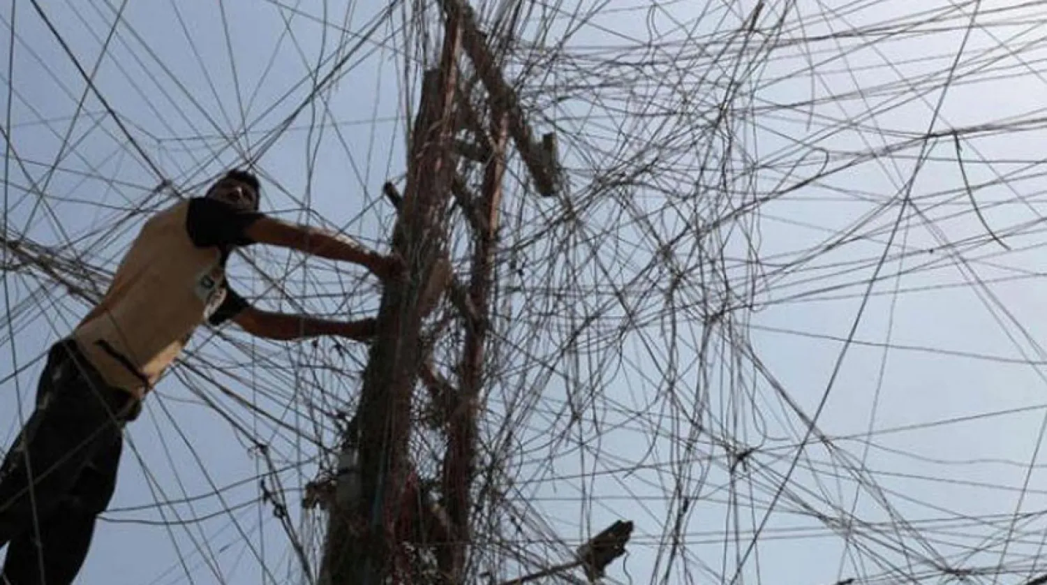 Bağdat’ın doğusundaki Sadr şehrinde elektrik kabloları arasında bir Iraklı işçi (AFP)