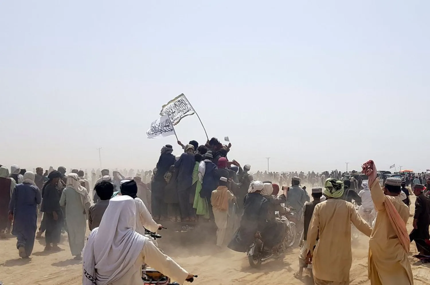 People standing on a vehicle hold Taliban flags as people gather near the Friendship Gate crossing point in the Pakistan-Afghanistan border town of Chaman, Pakistan July 14, 2021. REUTERS/Abdul Khaliq Achakzai
