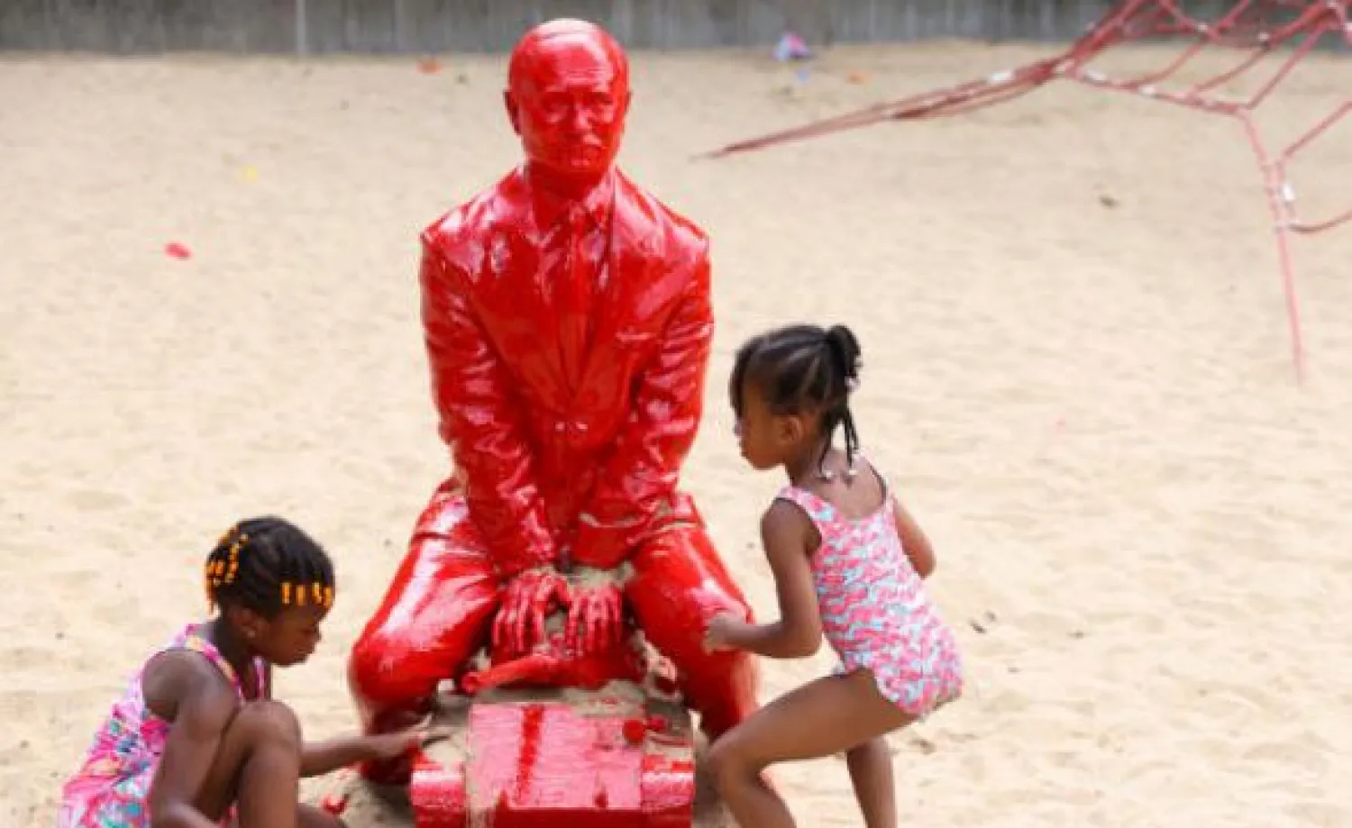 أطفال يرشون المياه ويلقون الرمال على التمثال (رويترز)