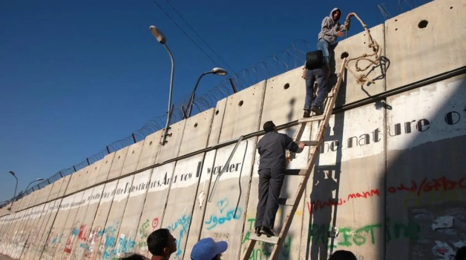 Palestinian men climb a section of Israel's separation barrier. (AFP file photo)
