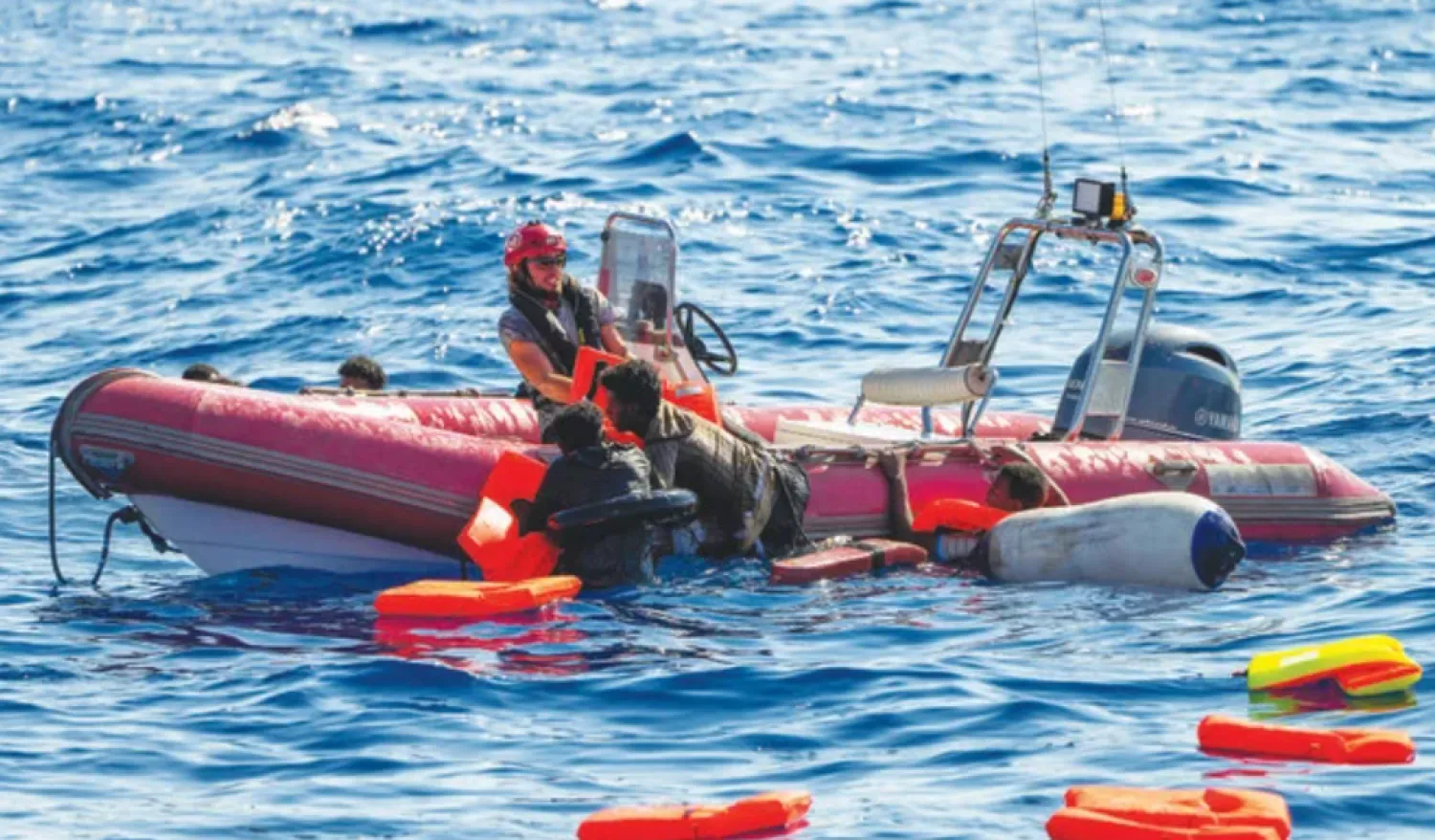 An NGO crew member helps migrants to get onboard after their wooden boat overturned during a rescue operation at the Mediterranean Sea. (AP)
