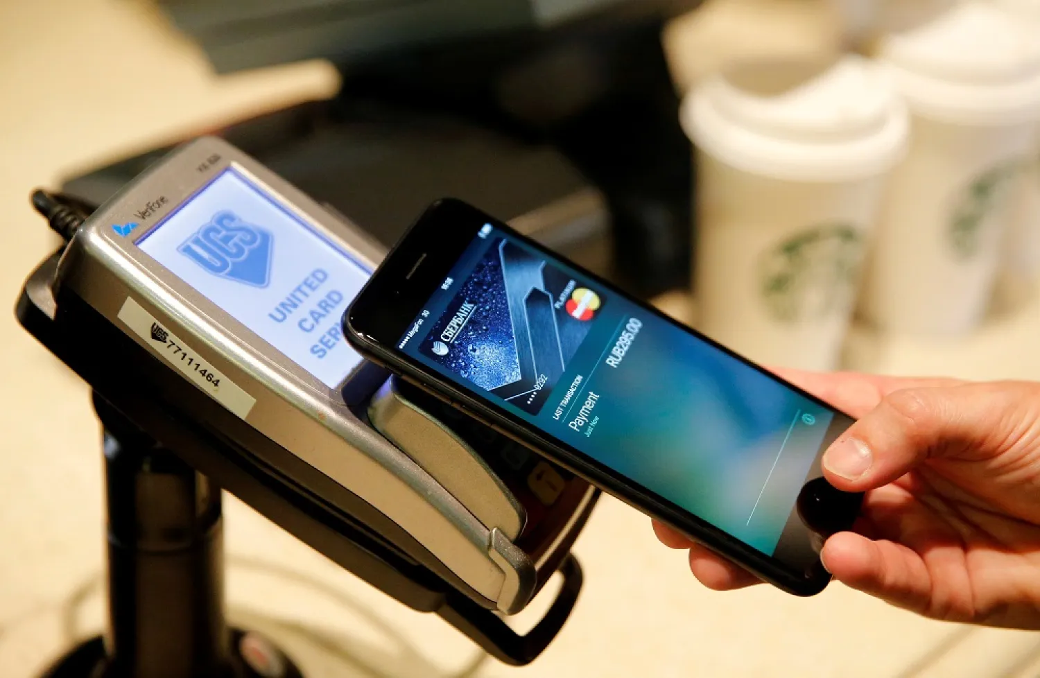 A man uses an iPhone 7 smartphone to demonstrate the mobile payment service Apple Pay at a cafe in Moscow, Russia, October 3, 2016. (Reuters)