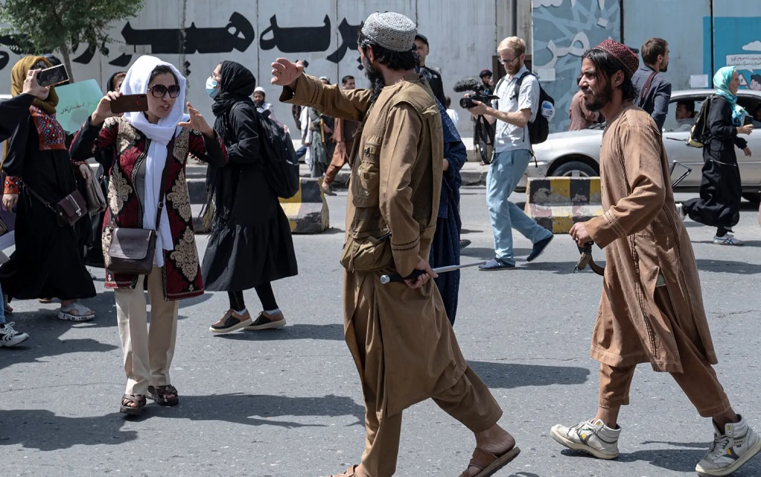 Taliban fighters walk as they fire in air to disperse Afghan women protesters in Kabul on August 13, 2022. (AFP)