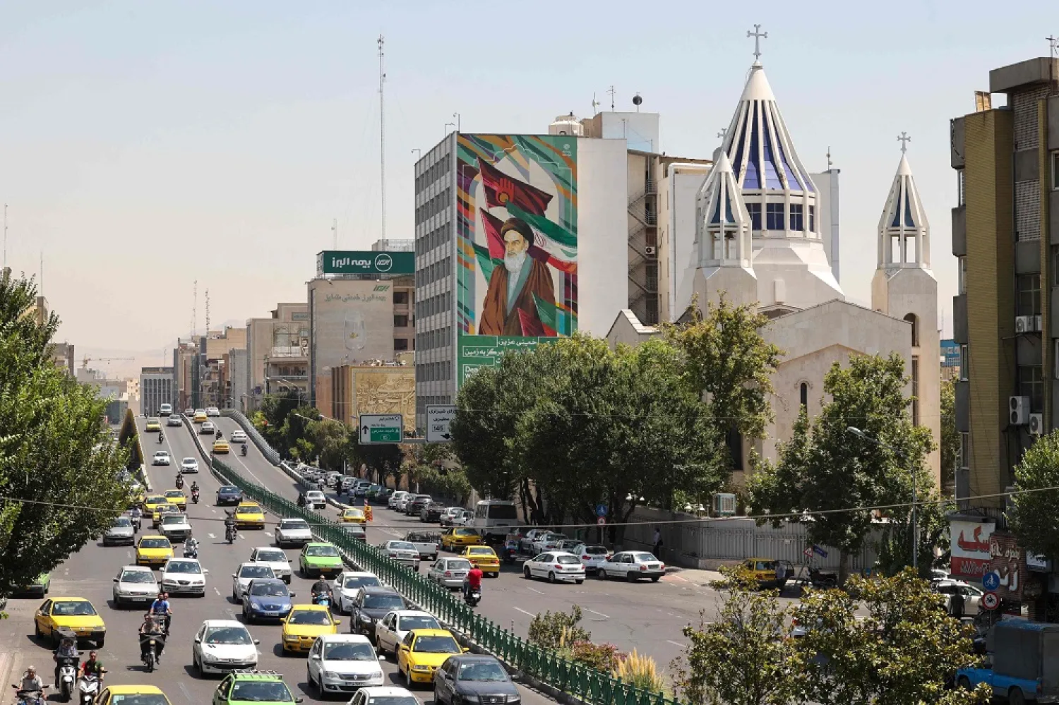Iranians drives past a billboard bearing the portrait of of the late supreme leader Khomeini in the capital Tehran on August 13, 2022. (AFP)