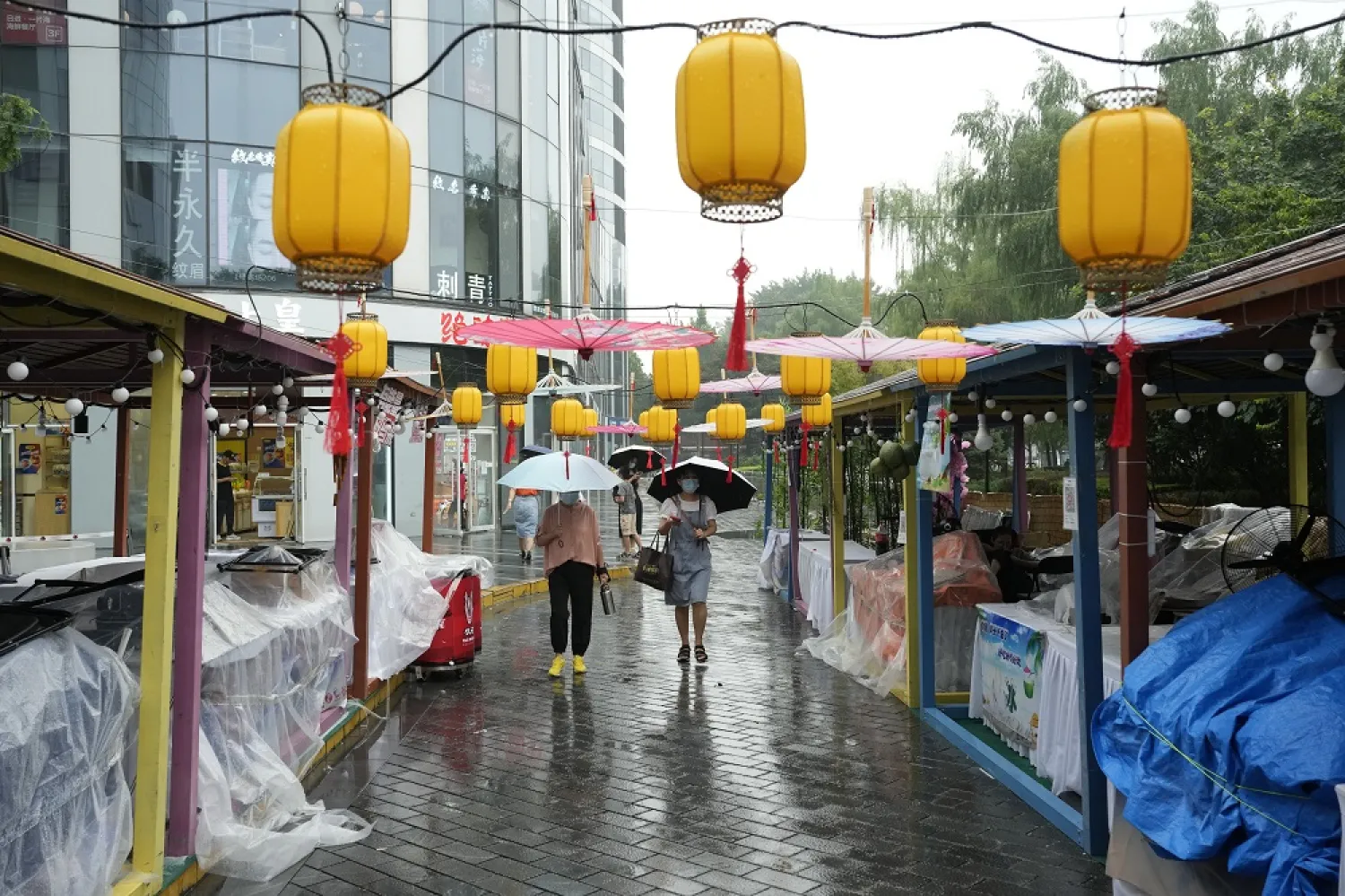 Residents walk near a bazaar closed due to the rain in Beijing, Sunday, Aug. 14, 2022. (AP)