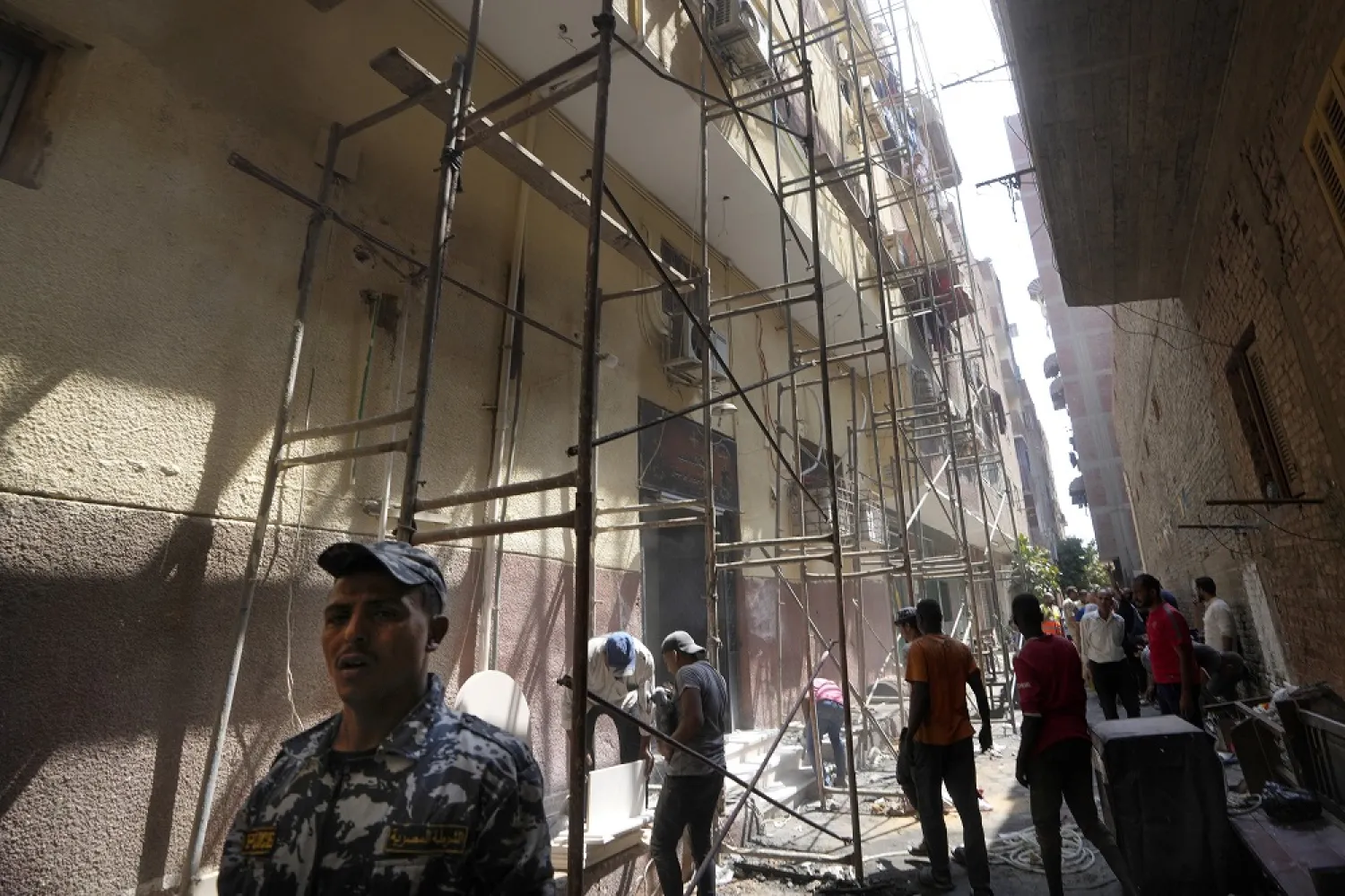 Police officers and workers are seen at the site of the Abu Sifin church under scaffolds, a day after a fire killed over 40 people and injured at least 14 others, in the densely populated neighborhood of Imbaba, in Cairo, Egypt, Monday, Aug. 15, 2022. (AP)