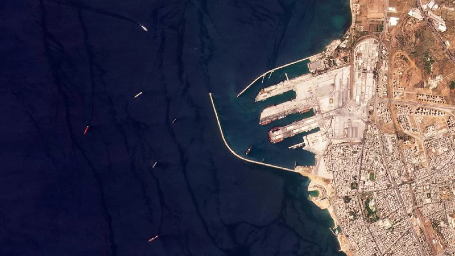 This satellite image from Planet Labs PBC shows the Russian-flagged cargo ship SV Konstantin, the red vessel the furtherest left, off the port in Tartus, Syria, Wednesday, Aug. 17, 2022.  (Planet Labs PBC via AP)

