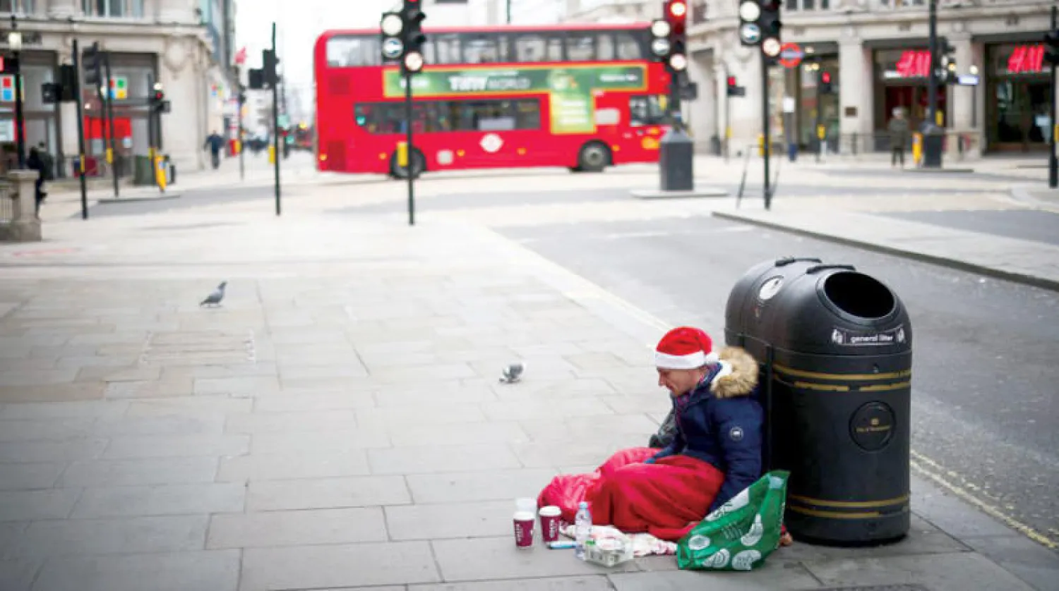 رجل بلا مأوى يجلس في شارع أكسفورد بالعاصمة البريطانية لندن (رويترز)