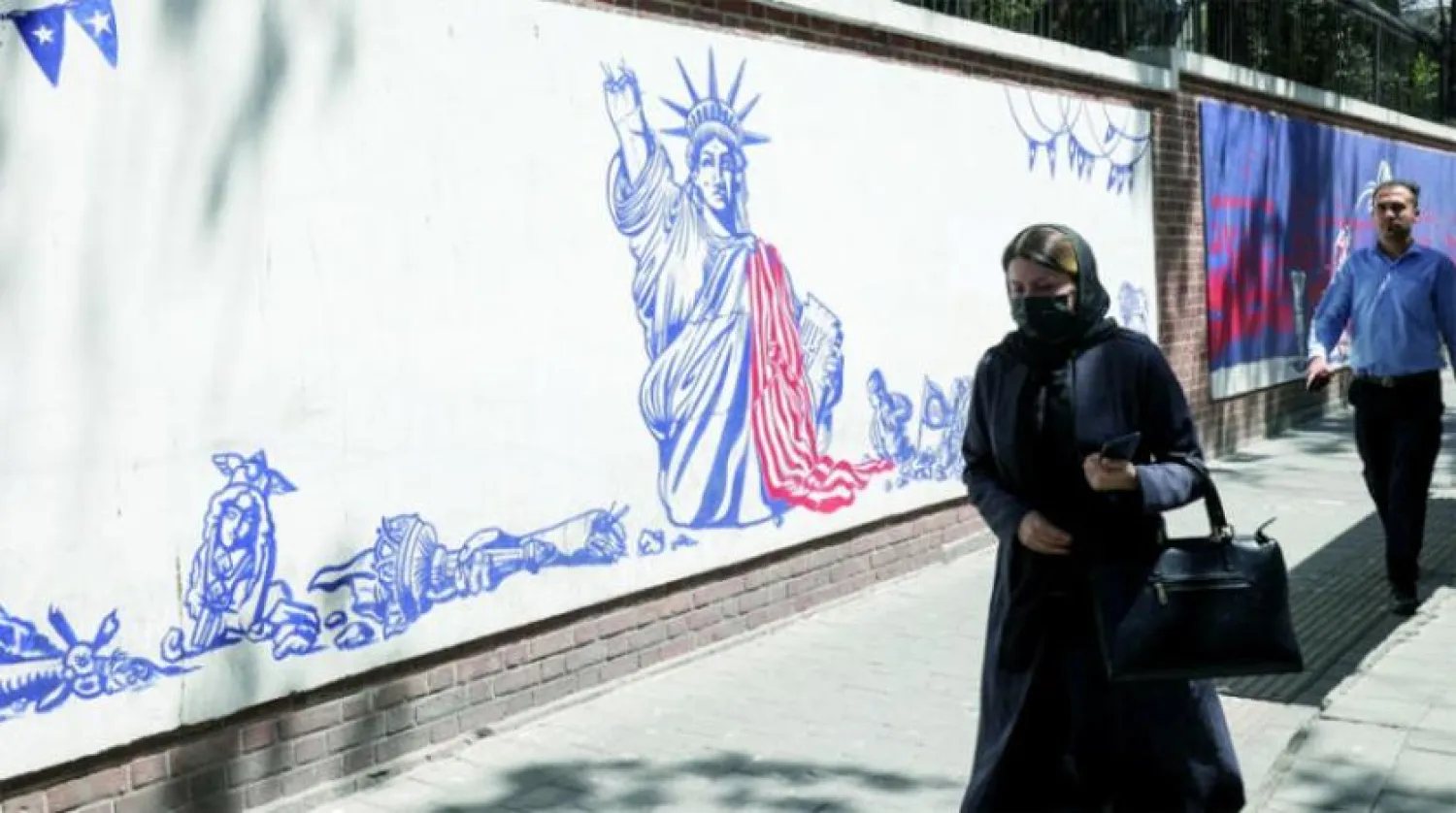 An Iranian woman walks near an anti-American mural on the wall of the former US embassy in Tehran on Tuesday. (Reuters)
