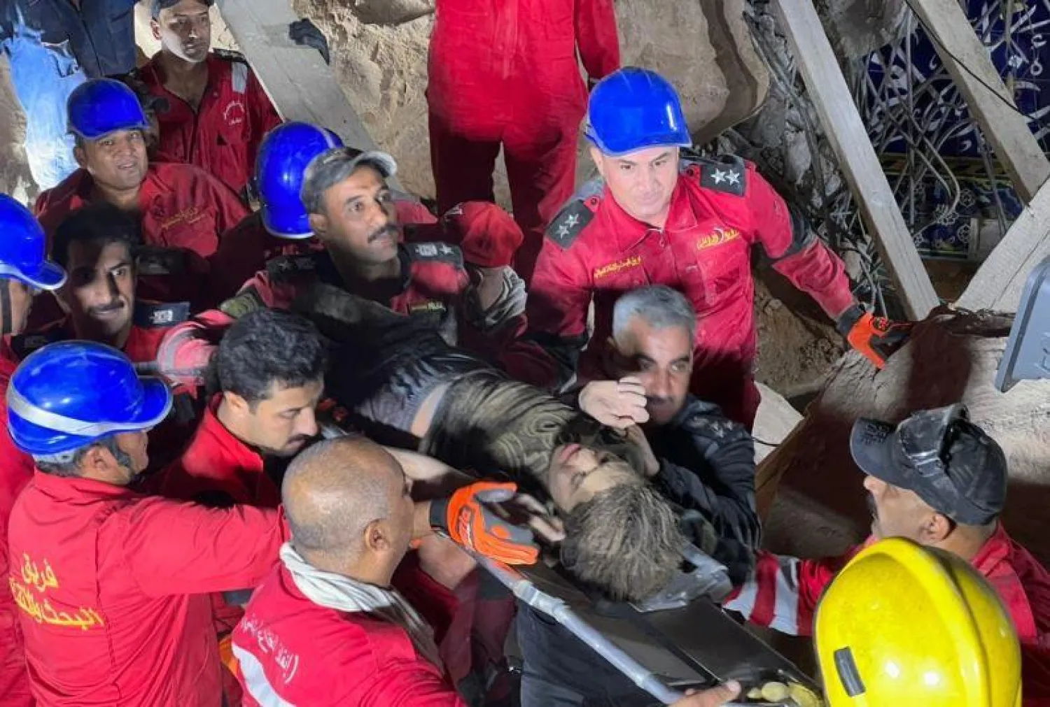 رجال الدفاع المدني العراقي وهم يُخرجون طفلة من تحت الأنقاض في مزار كربلاء (واع)