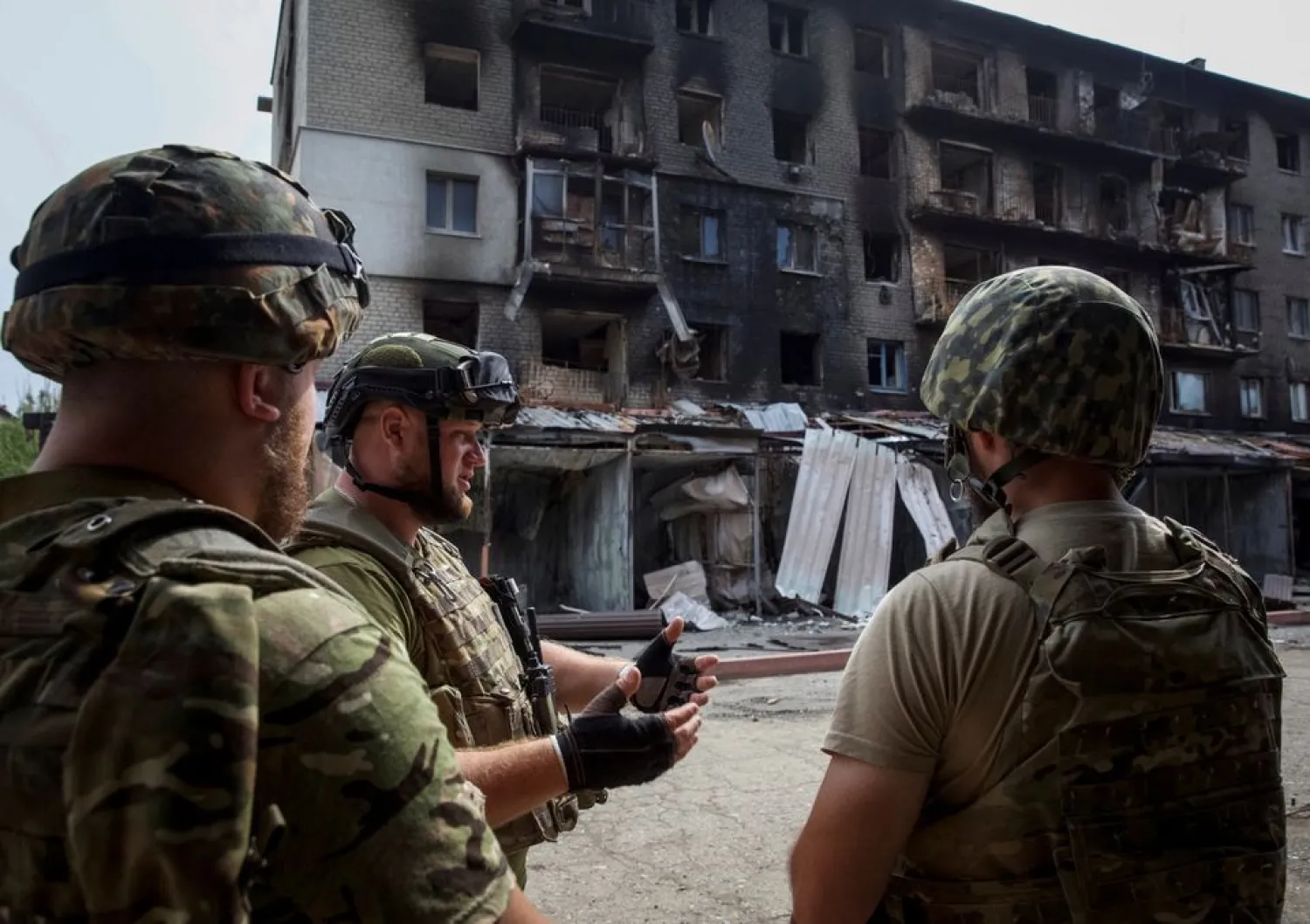 Ukrainian service members speak to each other in front of a residential building damaged by a Russian military strike, amid Russia's attack on Ukraine, in the town of Siversk, Donetsk region, Ukraine August 20, 2022. REUTERS/Anna Kudriavtseva




