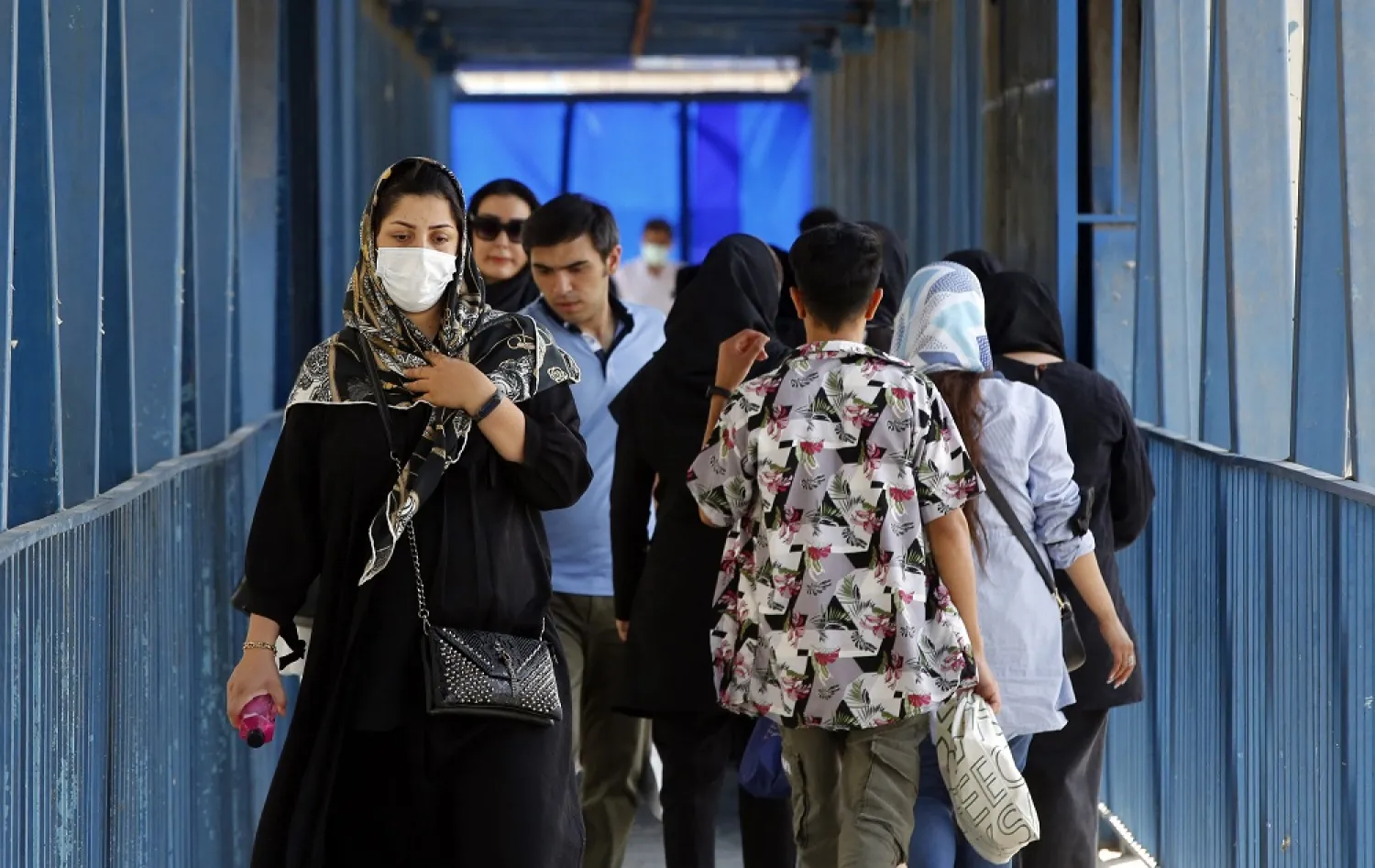 Iranians cross a pedestrian bridge street in the capital city of Tehran, on August 25, 2022. (AFP)