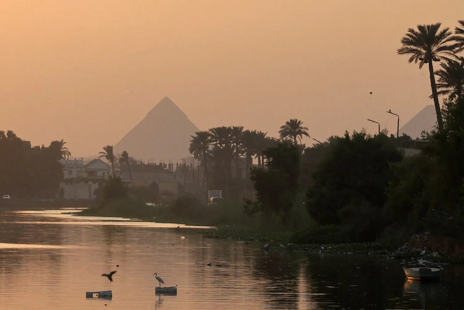 The Pyramid of Khufu, the largest of the Great Pyramids of Giza, is seen before sunset during high temperature behind a canal which flows into the River Nile on the outskirts of Cairo, Egypt August 4, 2022. (Reuters)