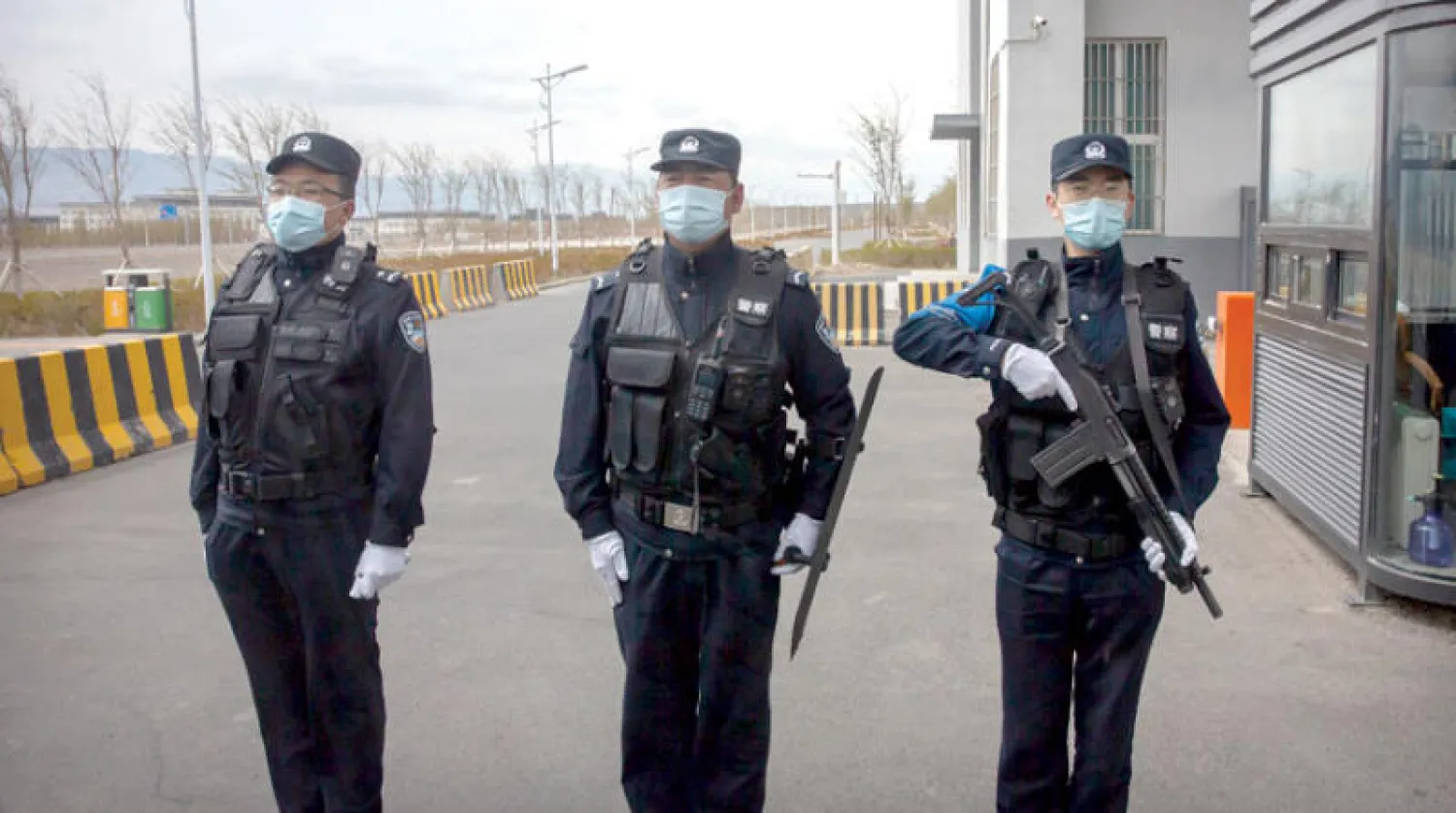 رجال شرطة صينيون يقفون خارج «مركز للتدريب المهني» في شينجيانغ في أبريل 2021 (أ.ب)