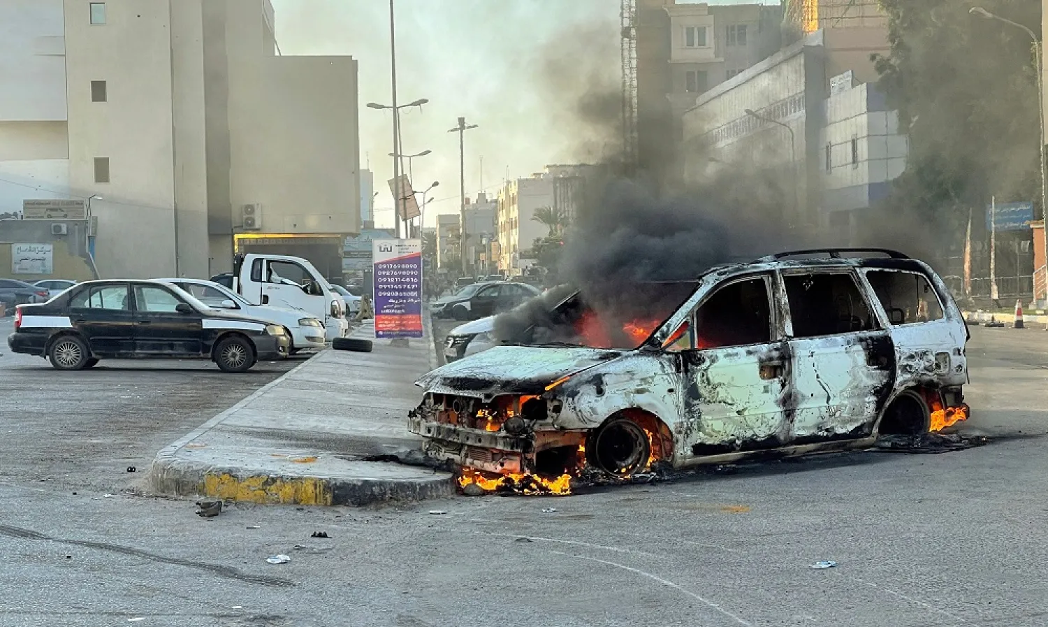 Damaged vehicles are pictured in a street in the Libyan capital Tripoli on August 27, 2022, following clashes between rival Libyan groups. (AFP)
