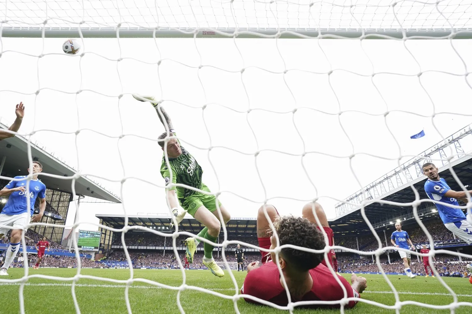 Everton's goalkeeper Jordan Pickford saves a ball as Liverpool's Roberto Firmino falls in the net during the English Premier League match between Everton and Liverpool at Goodison Park, Liverpool, England, Saturday, Sept. 3, 2022. (AP)